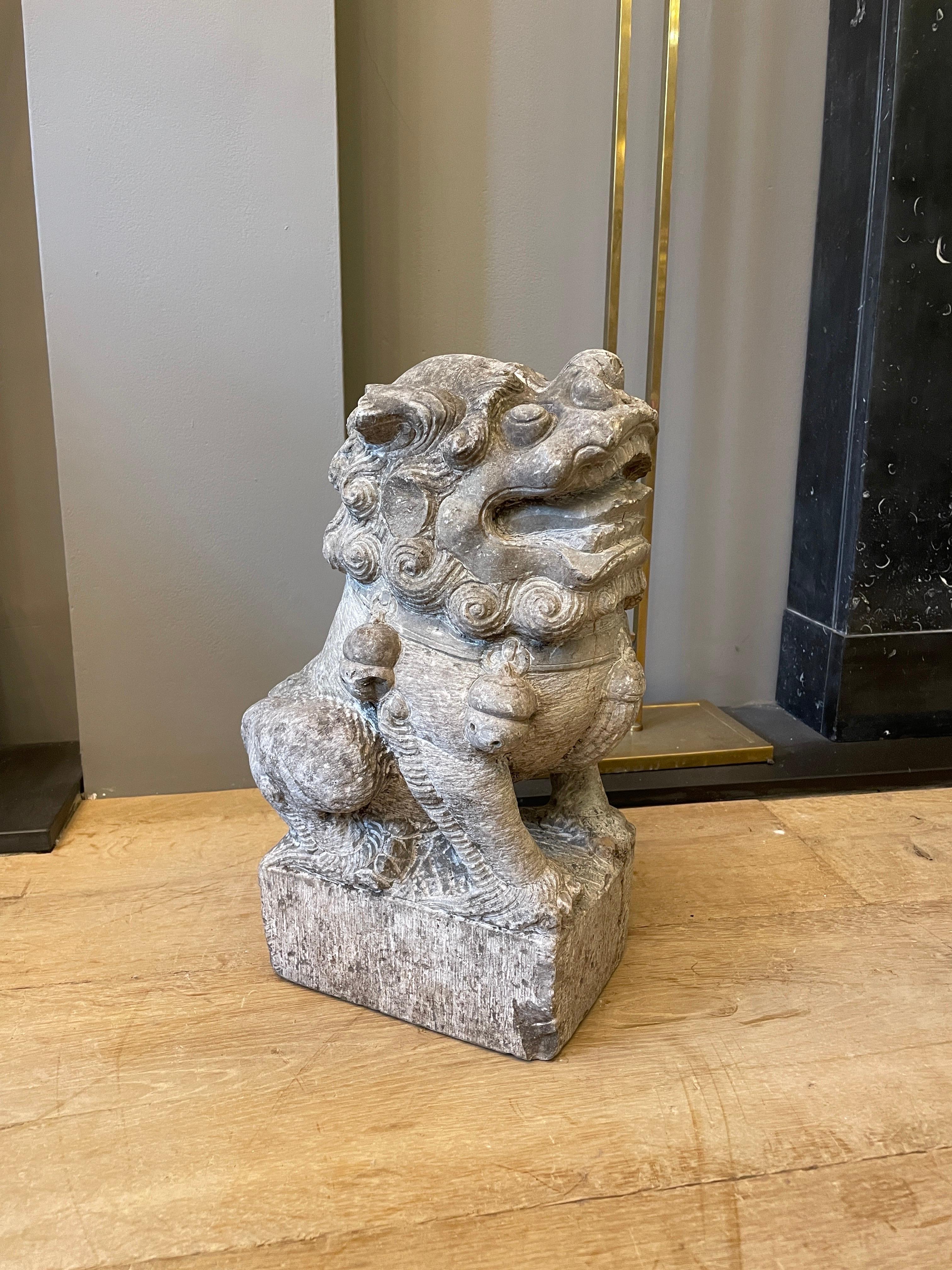 A well carved Foo dog in a hard limestone. Nicely weathered dating it mid 20th century. 
Chinese guardian lions, or imperial guardian lions, are a traditional Chinese architectural ornament, but the origins lie deep in much older Indian Buddhist