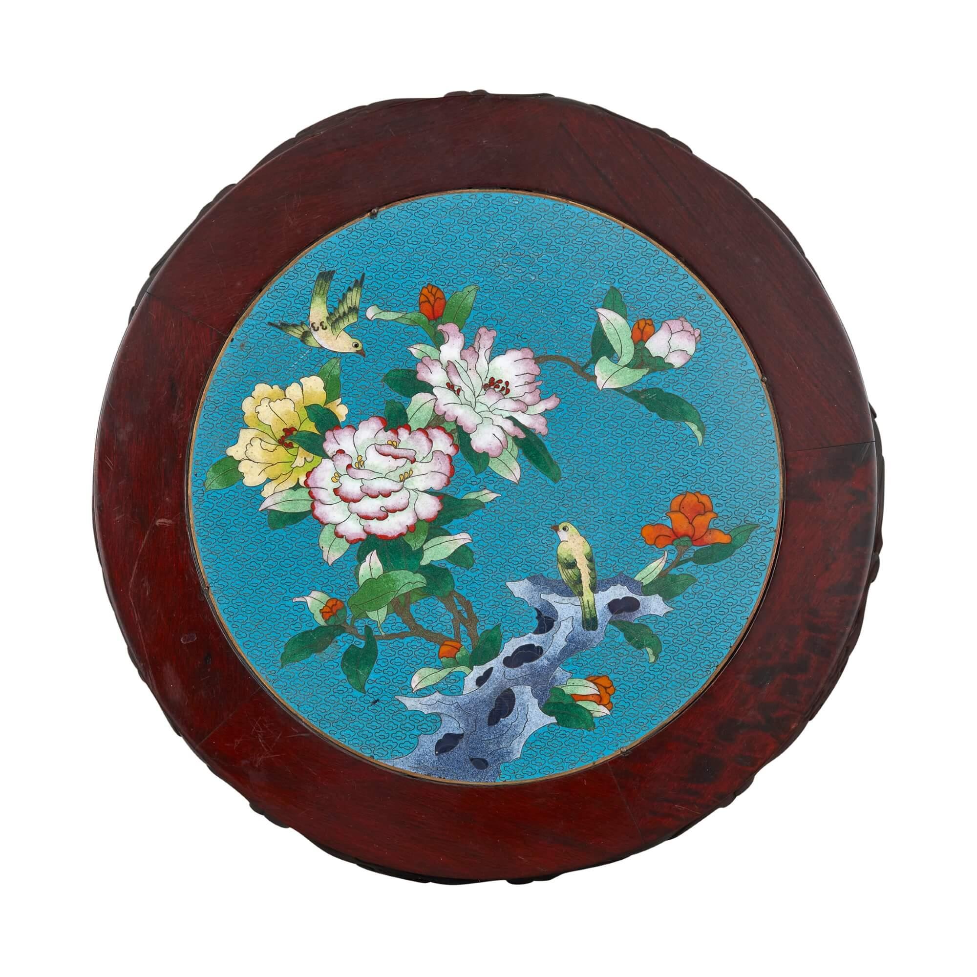 A Chinese cloisonné enamel inset circular carved hardwood pedestal
Chinese, early 20th century
Measures: Height 34cm, diameter 45cm

Made in China in the early twentieth century, this elegant yet humble piece is a carved hardwood stand, inlaid