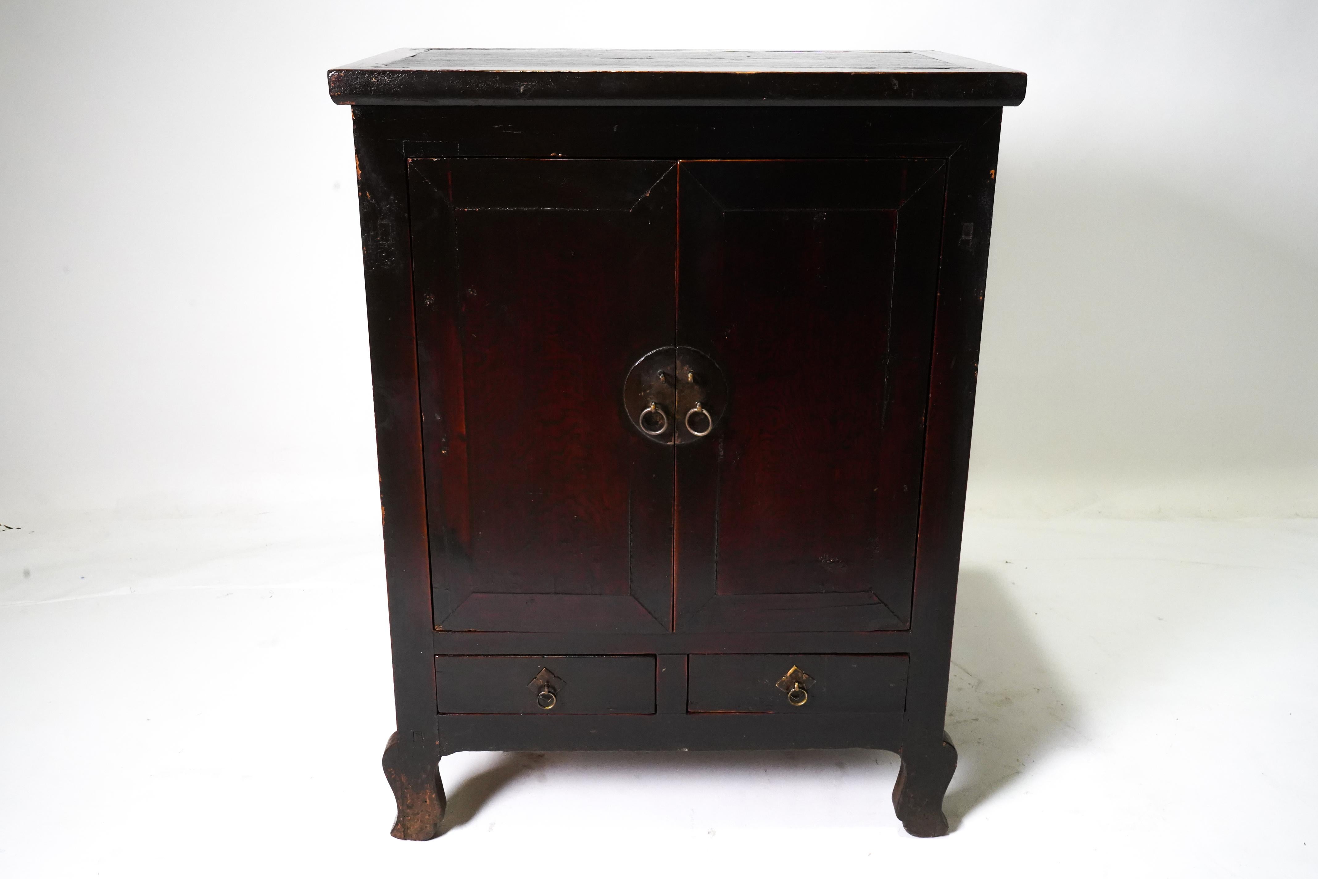 A rare all-original Chinese antique two-door clothing armoire with original brass lock plate and drawer pulls.  The gently aged and patinated oxblood lacquer is fully intact, still protecting the solid elm wood doors and frame.  This piece has great