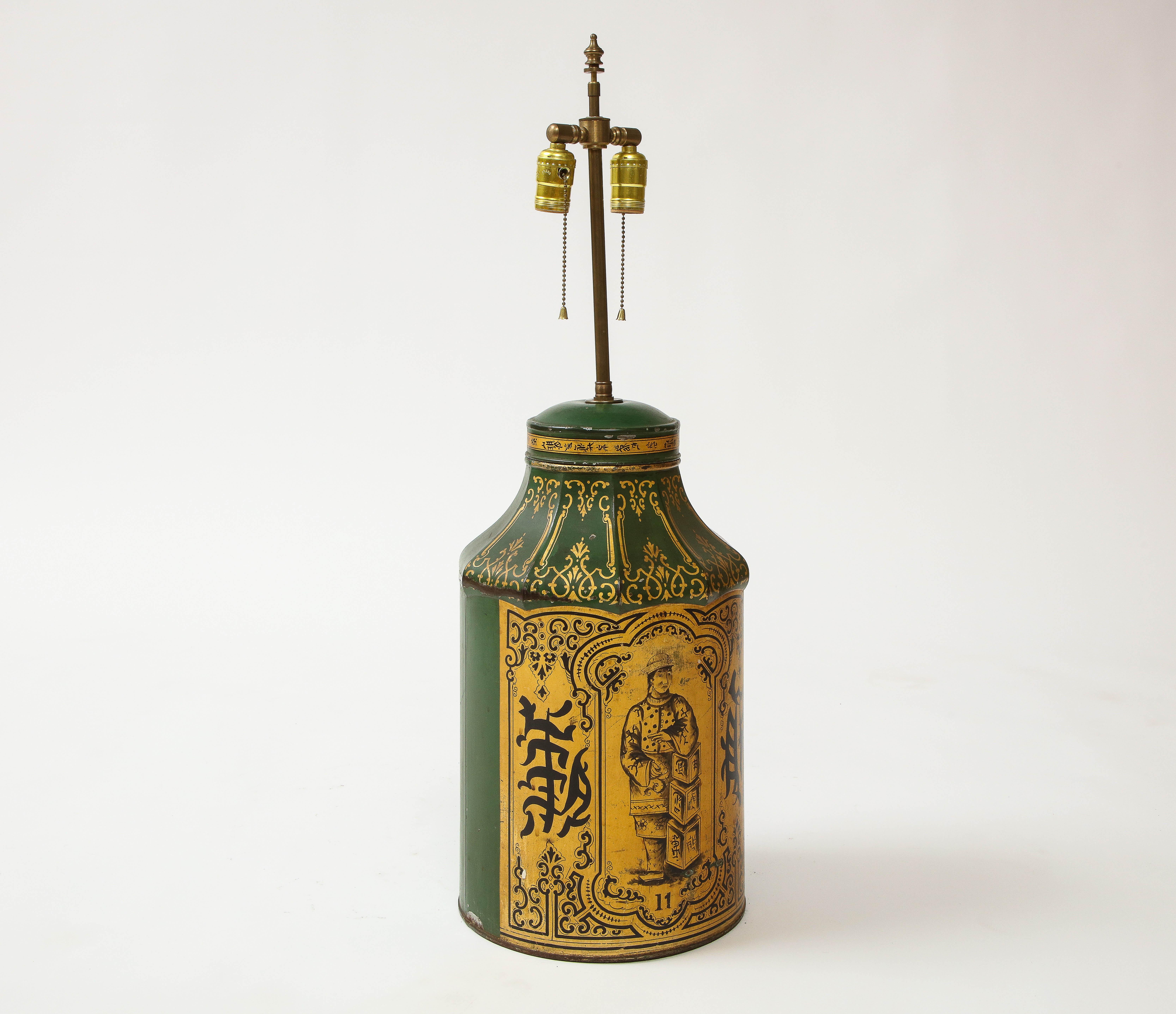 Of cylindrical form with incurved top; elaborately decorated with a central cartouche enclosing a Mandarin figure leaning against tea chests set above the number 11, flanked by pseudo-Chinese characters. Later mounted as a lamp with brass double