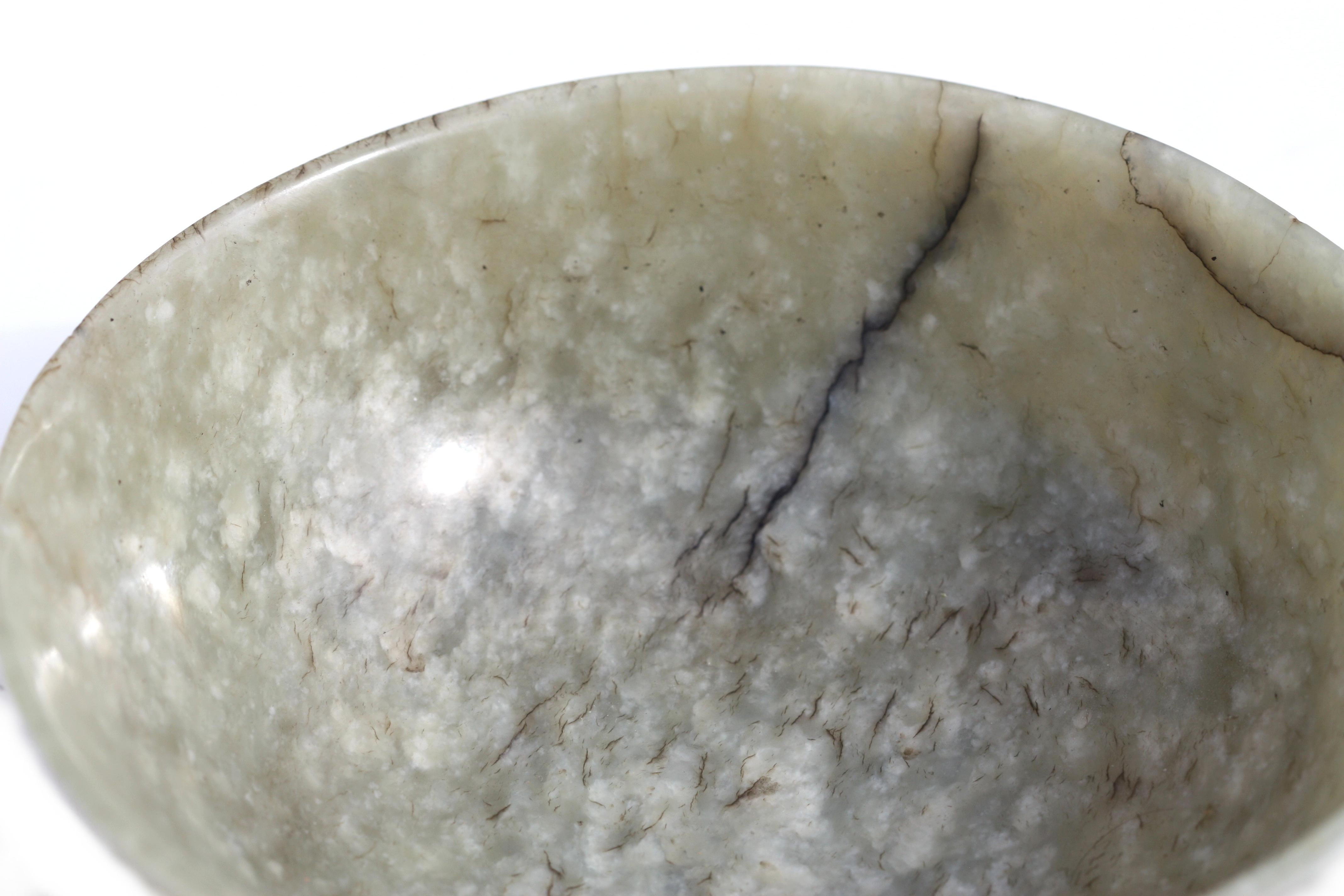 A Chinese grey jade imperial style bowl.
The mottled grey stone with white and dark speckles and cloudy inclusions, worked with deep rounded sides rising from a slightly splayed foot to a flared rim.

 