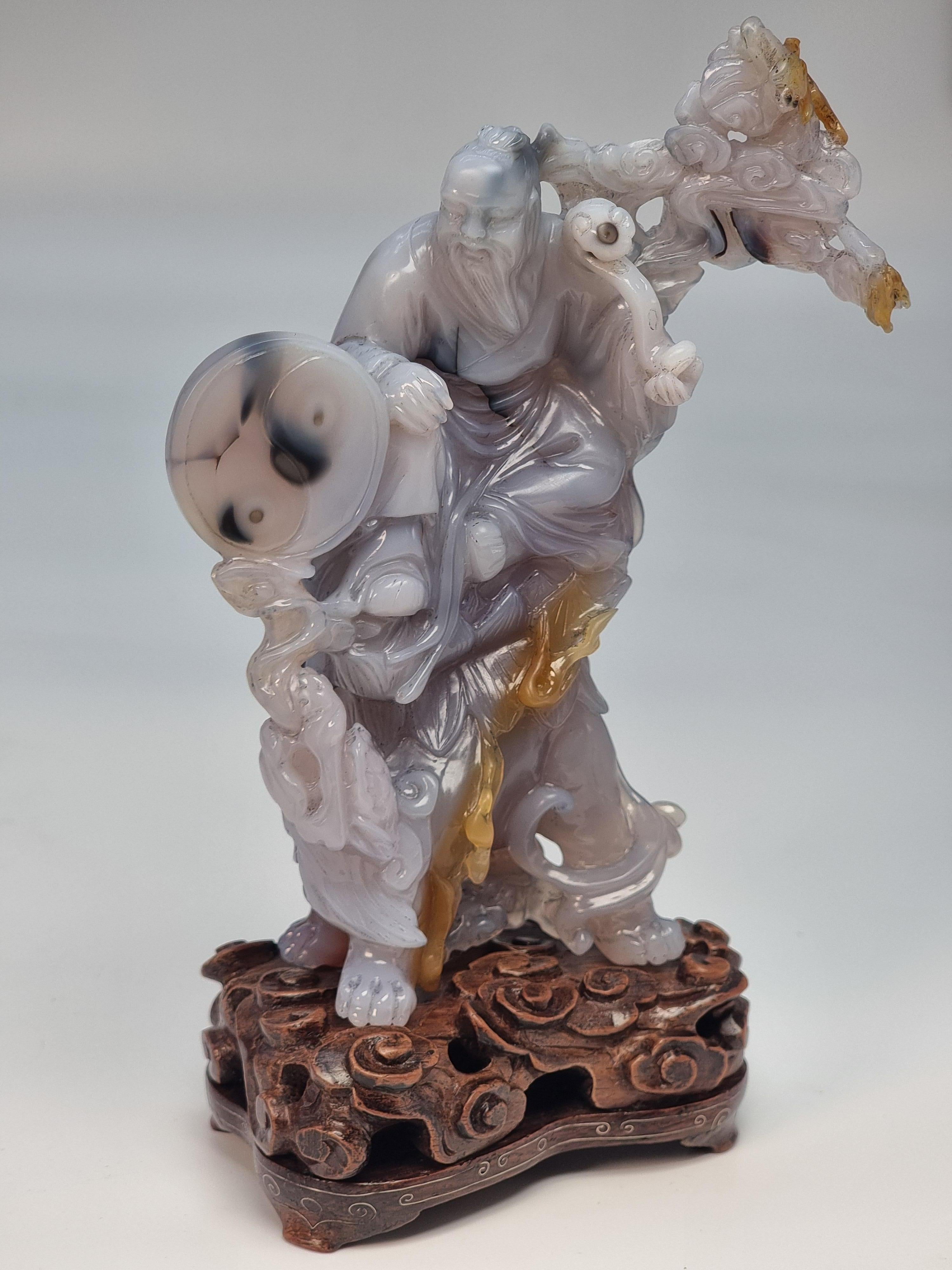 Cette étonnante sculpture chinoise a été taillée dans un seul bloc de pierre dure d'agate grise présentant des veines et des inclusions brunes et noires que l'artiste sculpteur a habilement utilisées pour mettre en valeur certaines parties de ce