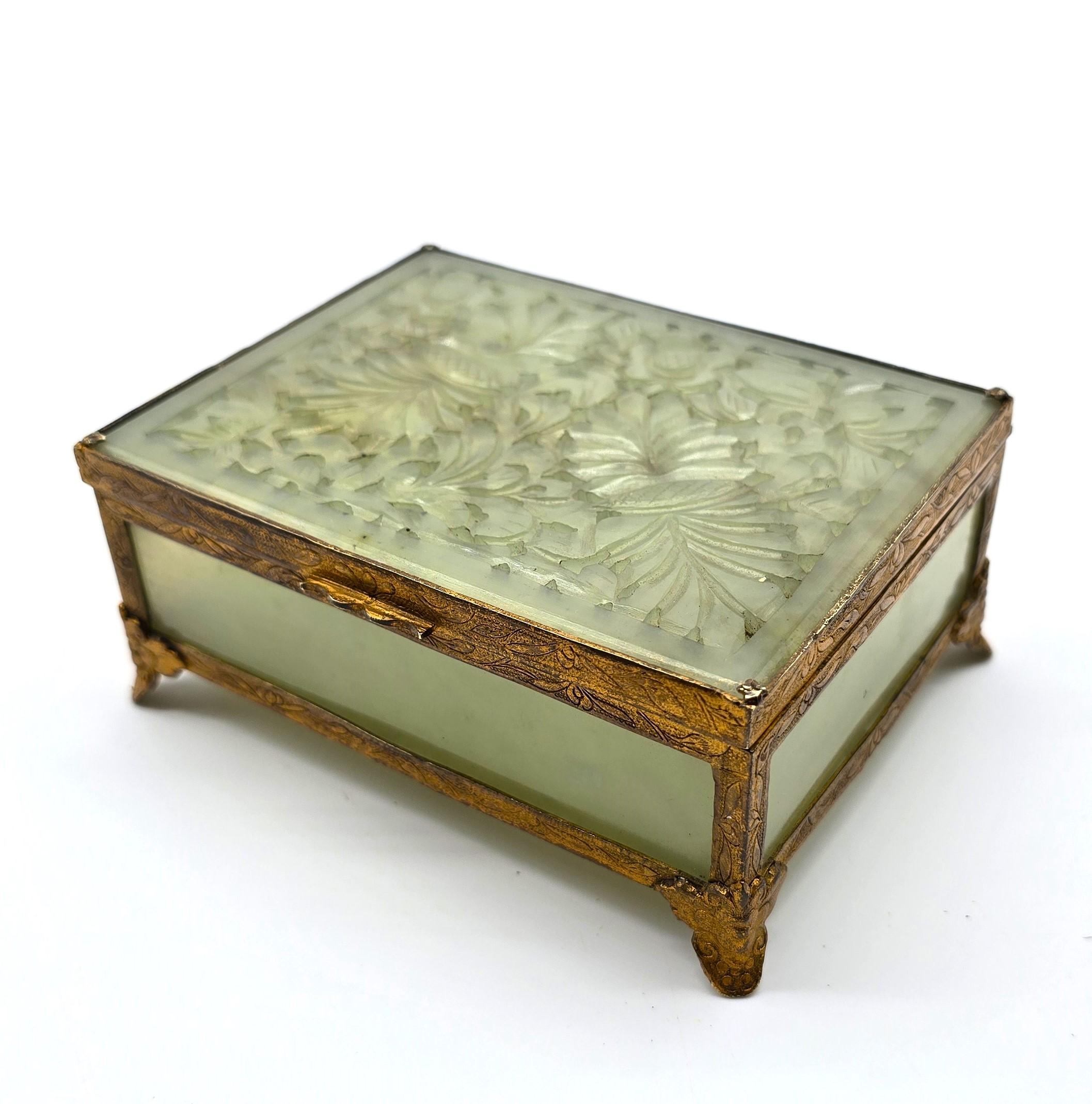 This very pleasing small early 20th century Chinese jewelry box is ideal for storing small pieces such as rings, etc.

The box is made from panels of pale green jade set into a gilt brass frame with a hinged lid. 

The whole metal frame is hand