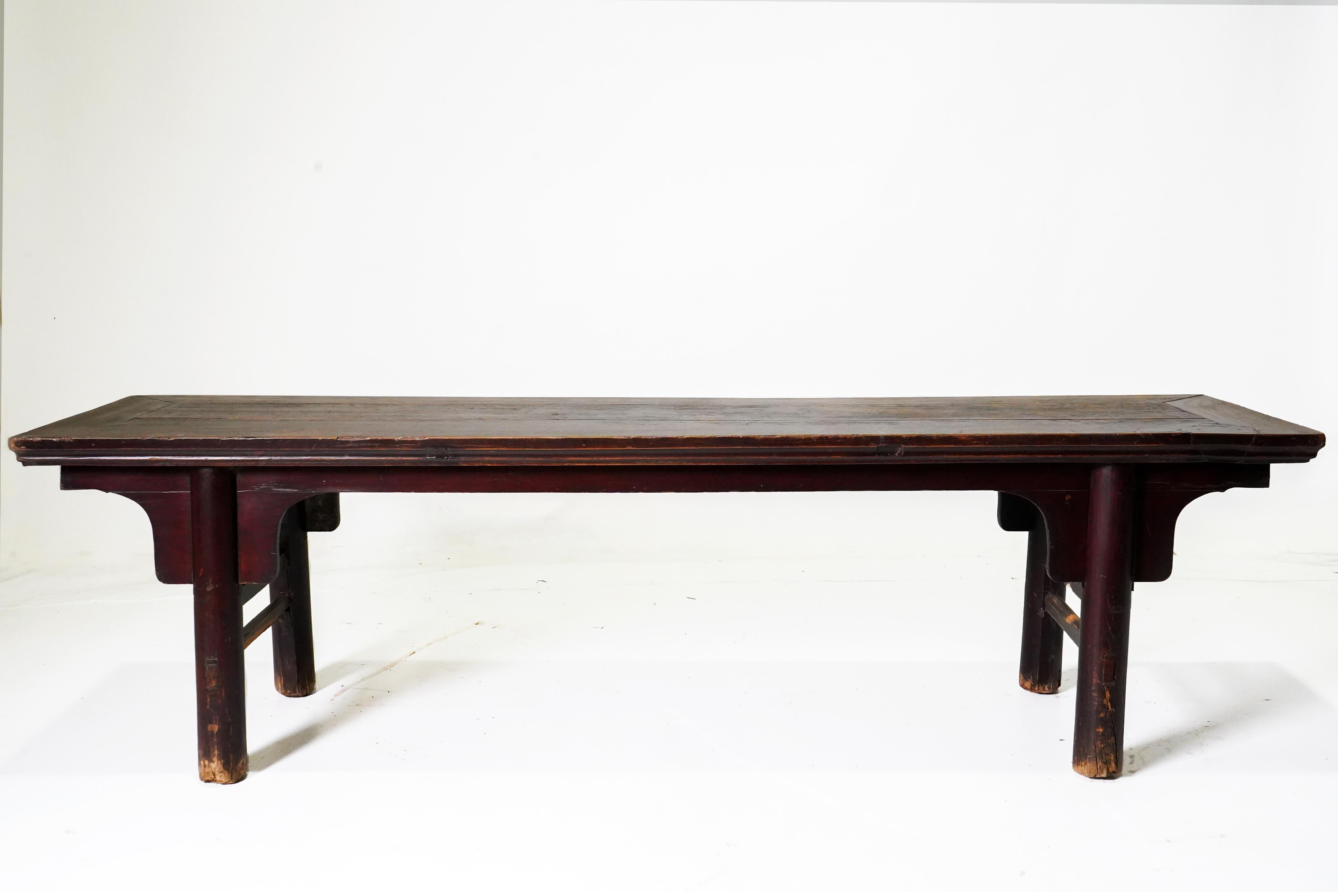 This long and graceful Chinese bench dates to the late 19th century and was made from northern elm using mortise-and-tenon joinery. It has a framed seat with a floating panel interior and is raised on splayed round legs reinforced by simple curved