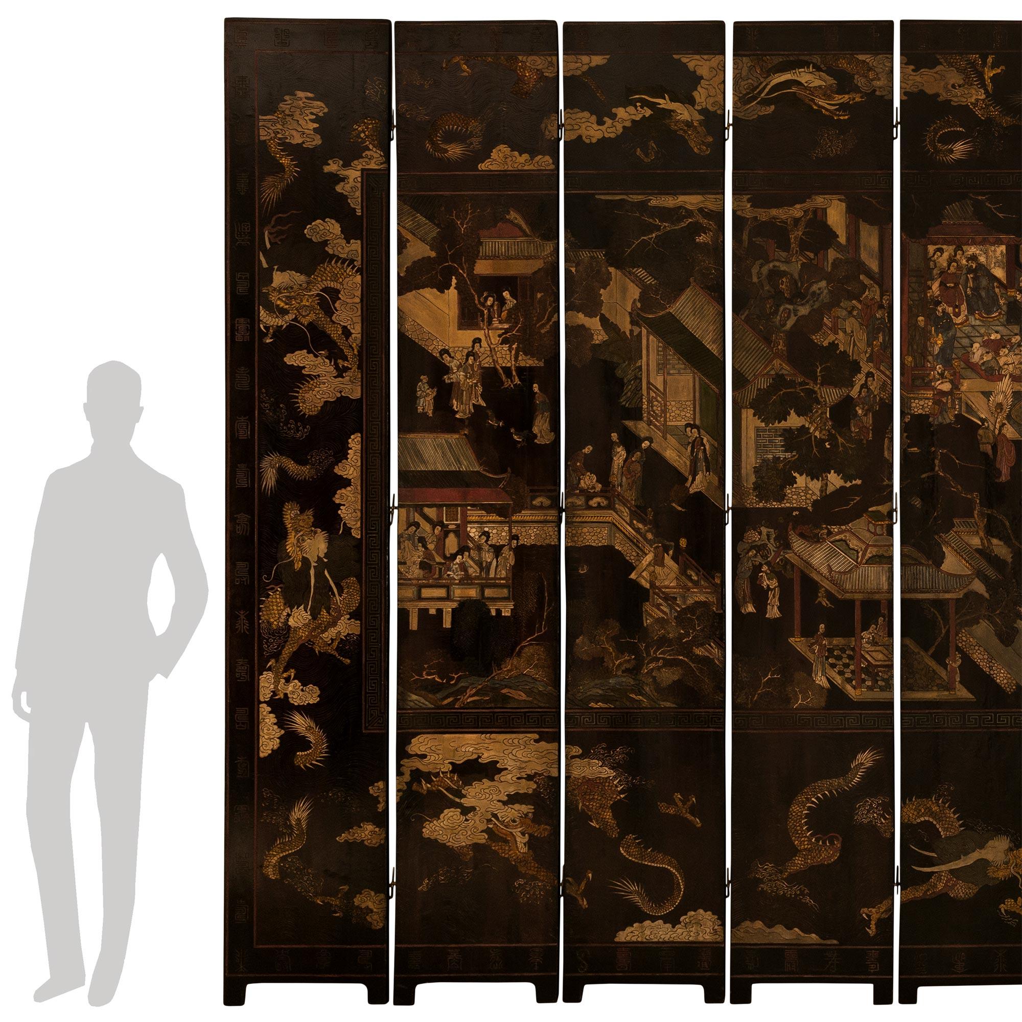 A monumentally scaled and most important Chinese mid 18th century Laquered Coromandel screen. This finely detailed ten panel screen, with its original tempera paint, showcases a collection of continuous scenes depicting a landscape with pagodas,