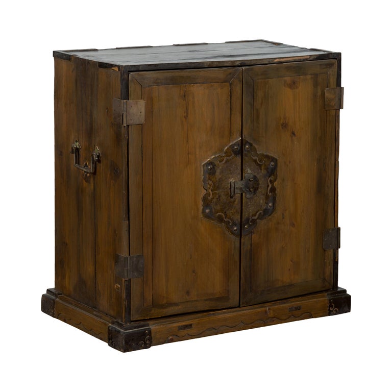 A Chinese Qing Dynasty period antique carrying chest from the 19th century, with ornate patinated brass floral-shaped hardware, two doors and lateral handles. Created in China during the Qing Dynasty, this carrying chest features a rectangular top