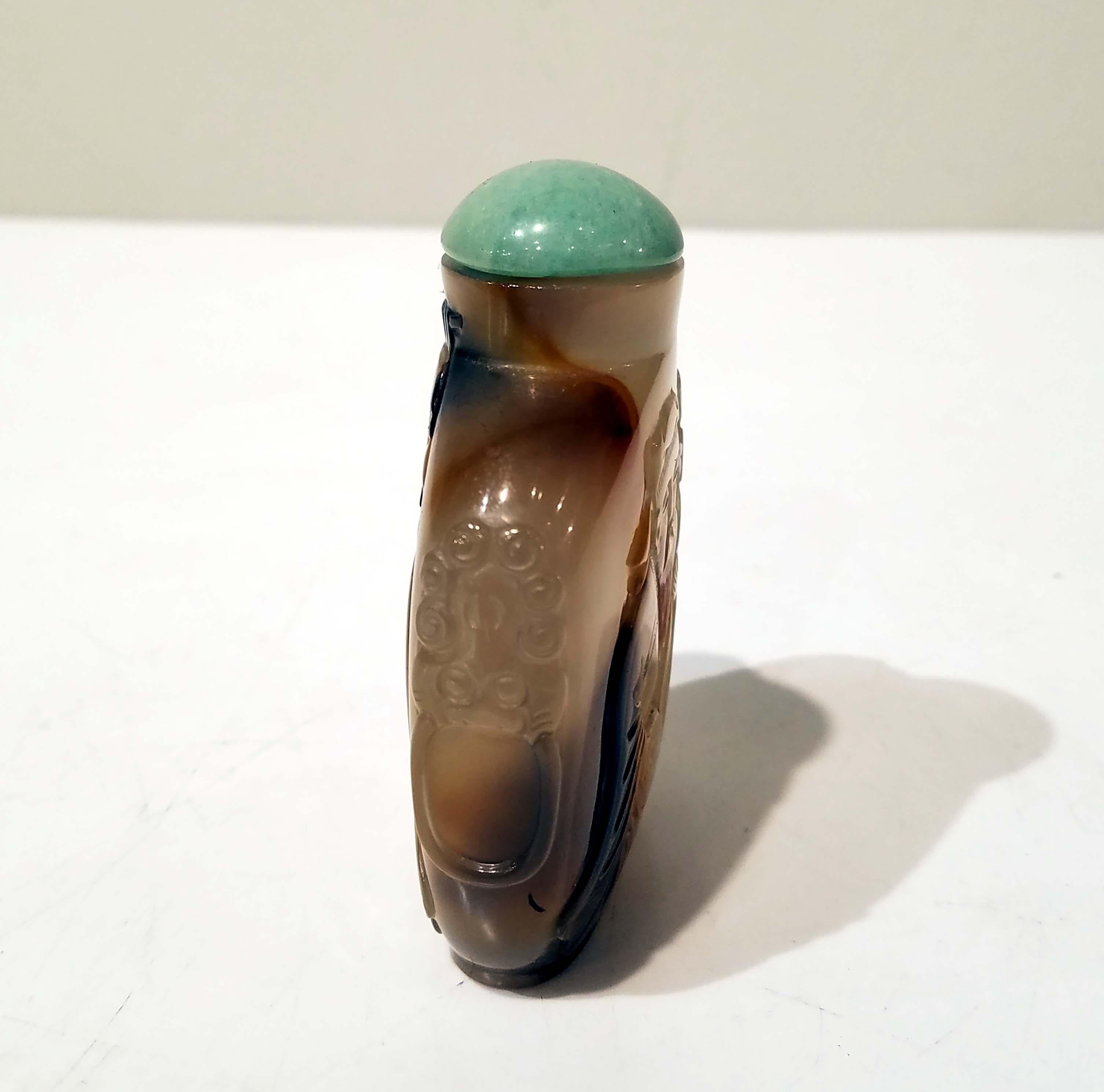 Chinese, circa 1750-1860. Well-hollowed, of rounded square form with a short cylindrical neck, flat lip, oval foot ring, employing the deeper color inclusions in the warm honey-toned matrix, carved to one side with a bearded man playing an