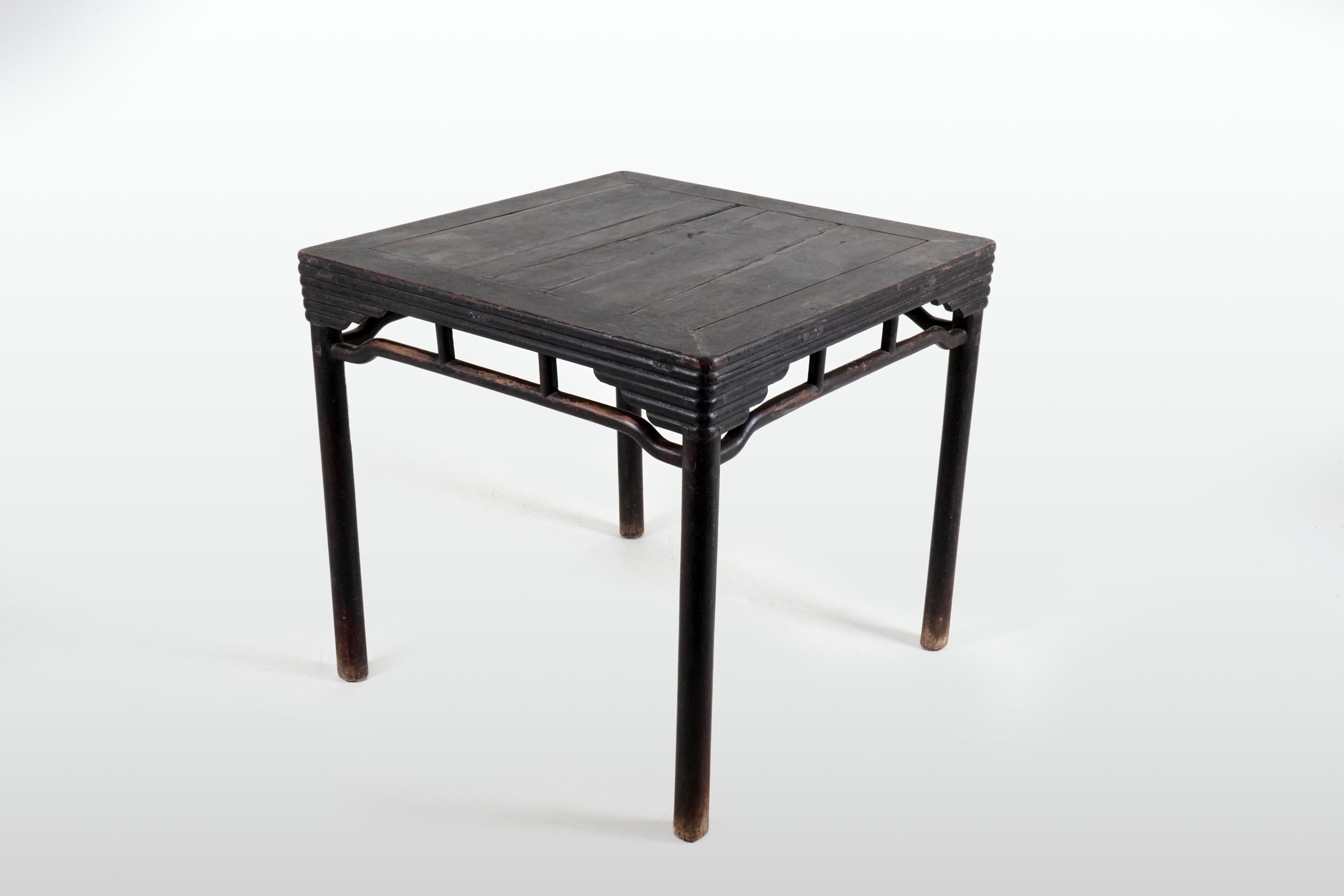 A game table from the 19th century with humpback stretchers, pillar legs and bamboo motif bundled crossmembers. Created in China during the Qing Dynasty in the 19th century, this sturdy table features a square planked top sitting above an openwork