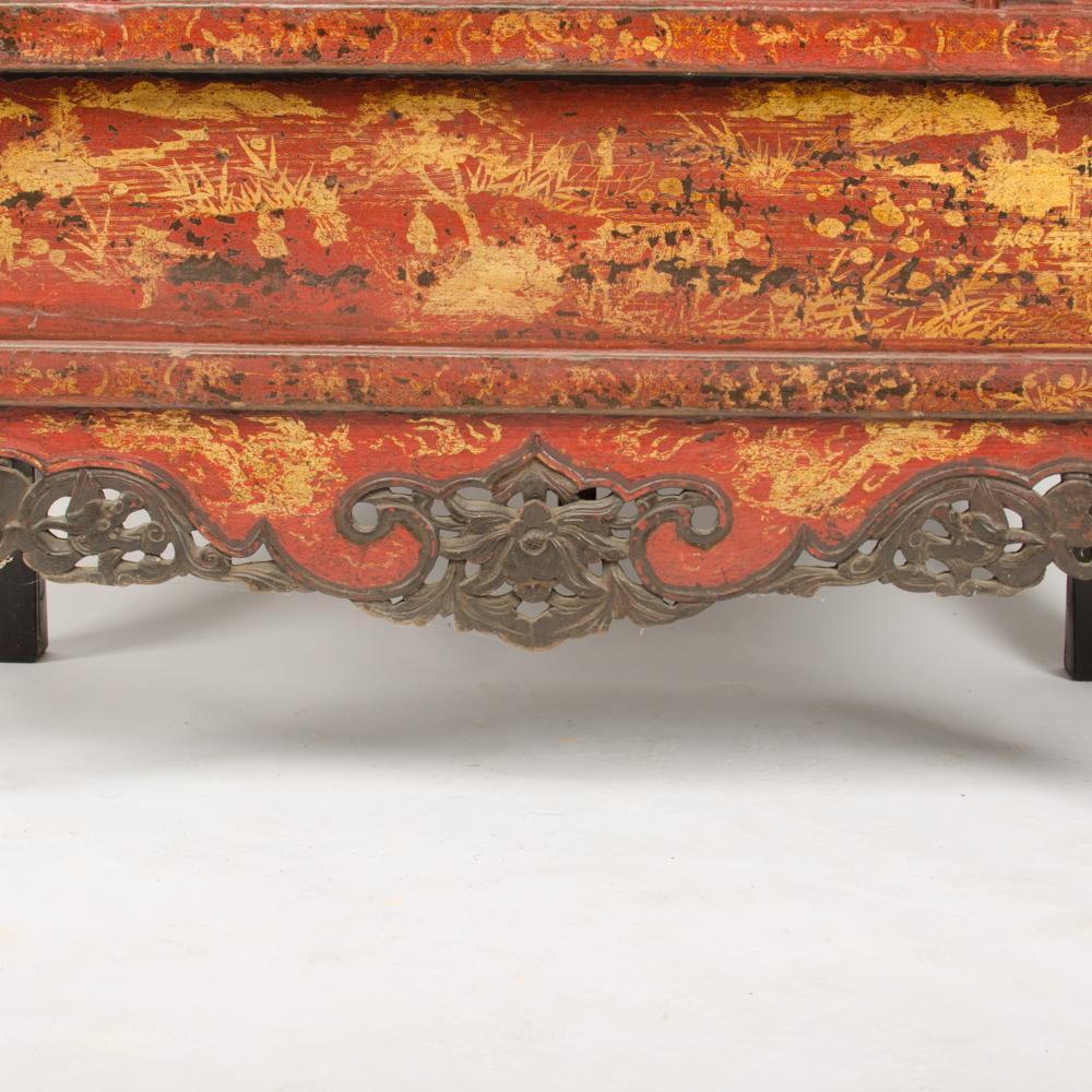 L'armoire à deux portes en chinoiserie laquée rouge est dotée de ferrures et d'ornements en laiton et d'un seul tiroir inférieur.