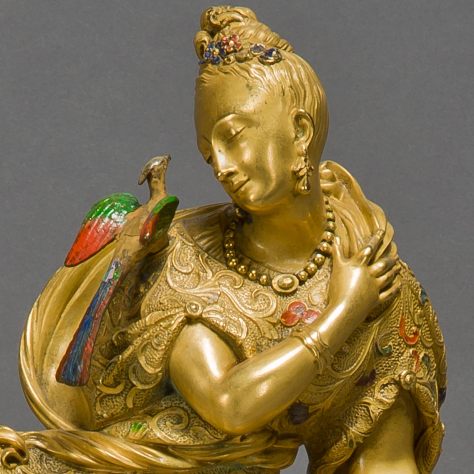 A rare Chinoiserie style gilt-bronze and enamel figural clock.

This elegant and sophisticated clock has a finely chiselled gilt-bronze case with gold and enamel highlights. It depicts a woman in Chinoiserie costume with an attendant bird of