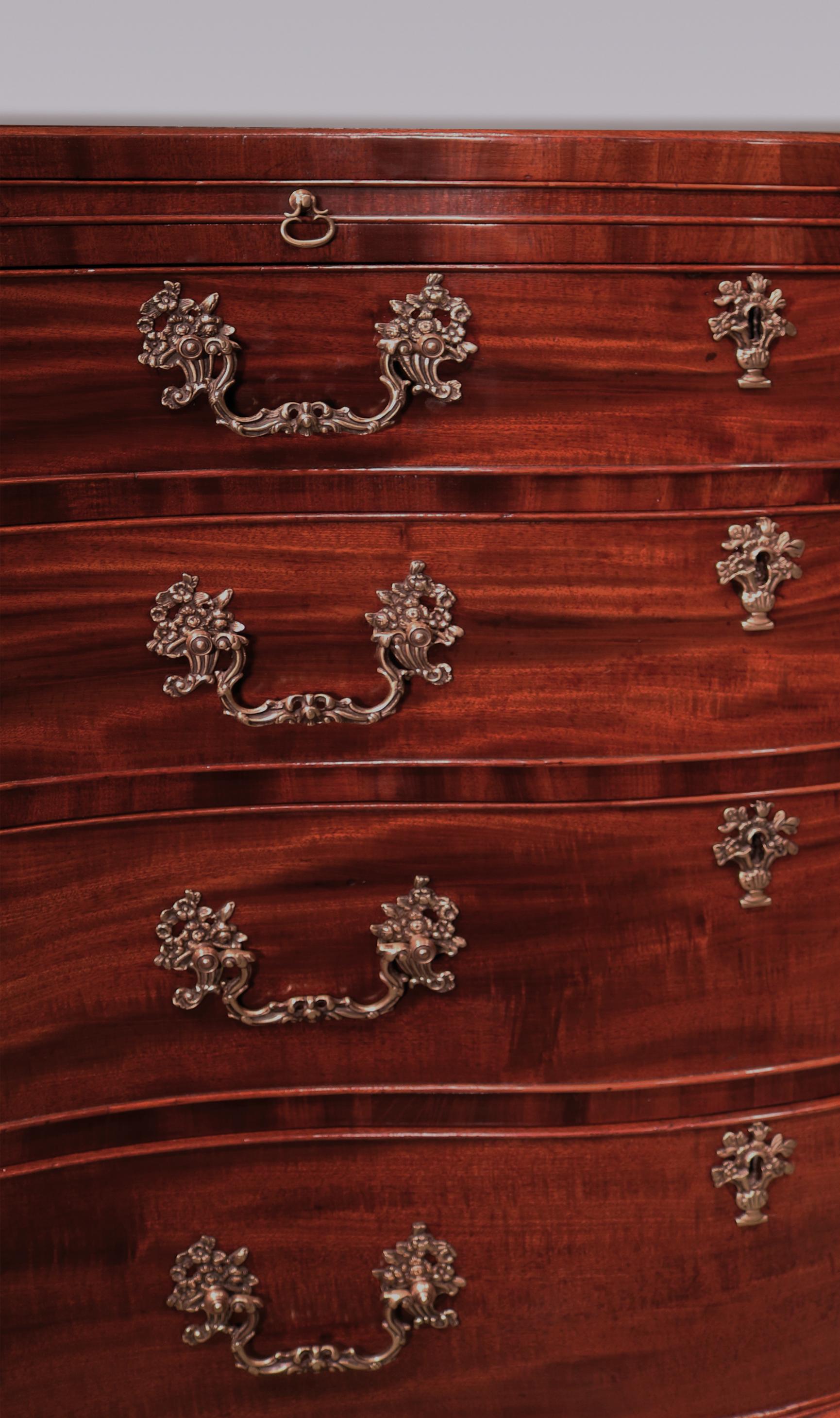 A mid-18th century Chippendale period well-figured mahogany serpentine chest, having caddy top above cockbeaded brushing slide and graduated drawers retaining original handles, flanked by blind fret canted corners, supported on well-shaped ogee