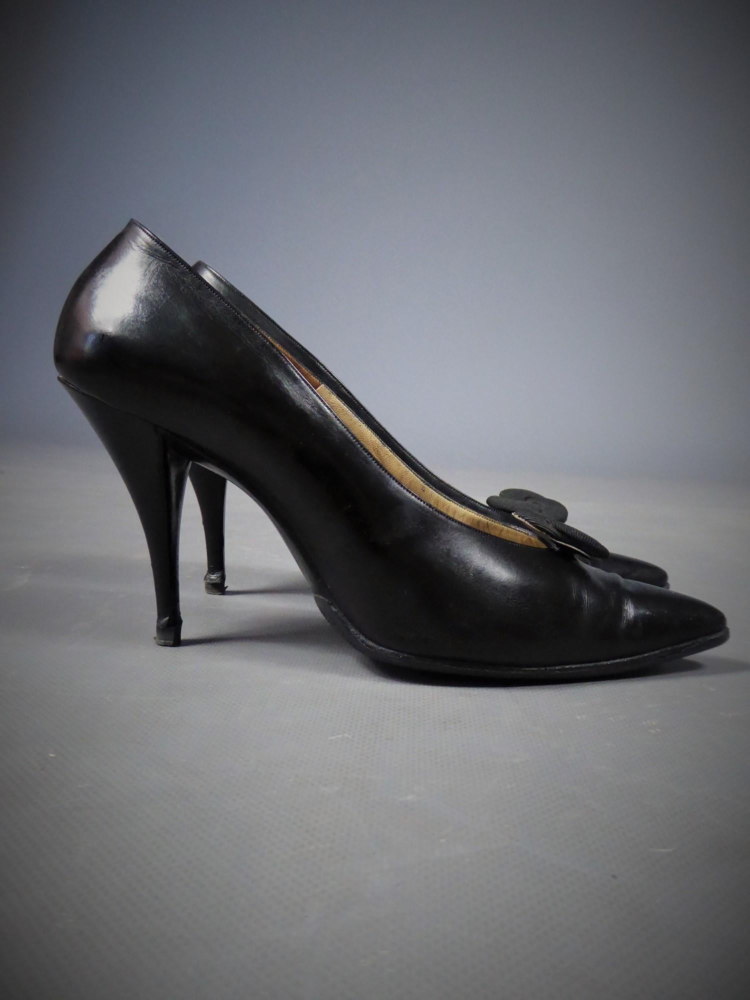 Circa 1960
France

Paire de talons de soirée Christian Dior par Roger Vivier en cuir noir brillant des années 60. Chaussures à talons aiguilles, de forme incurvée et pointue à l'avant, décorées d'une rosette amovible en soie cannelée noire ottomane.
