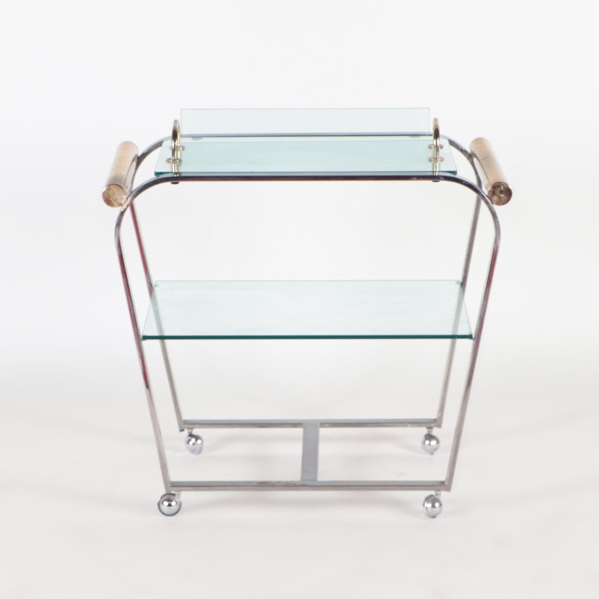 An elegant chrome and glass two-tier bar cart with brass details and removable tray C 1980.