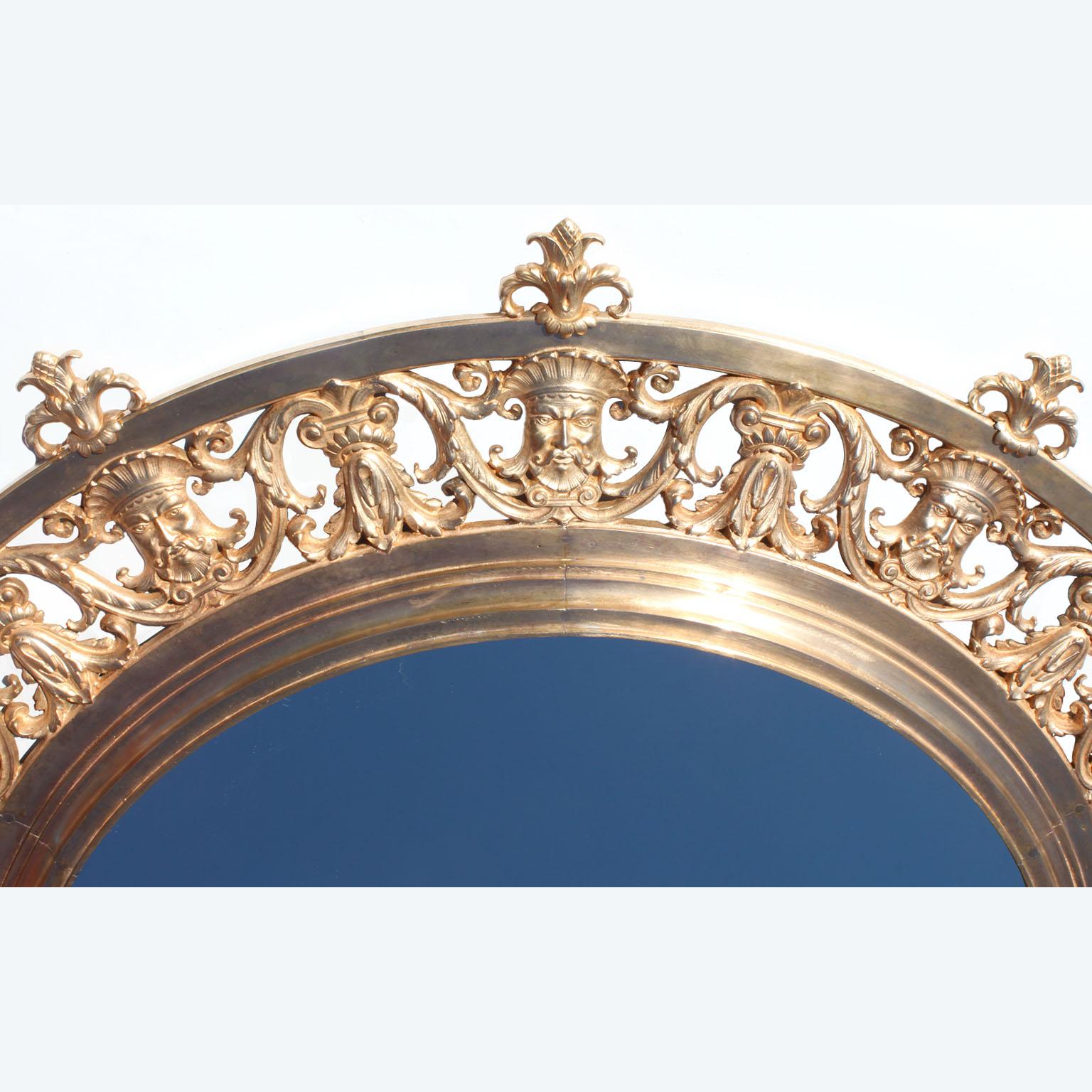 A fine and large circular 19th century Baroque Revival style gilt-bronze figural mirror. The ornately pierced foliate scrolled surround gilt-bronze frame decorated with allegorical male masks topped with acorns and centered with a circular mirror
