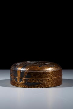 A circular gilt-lacquer box depicting a landscape scene