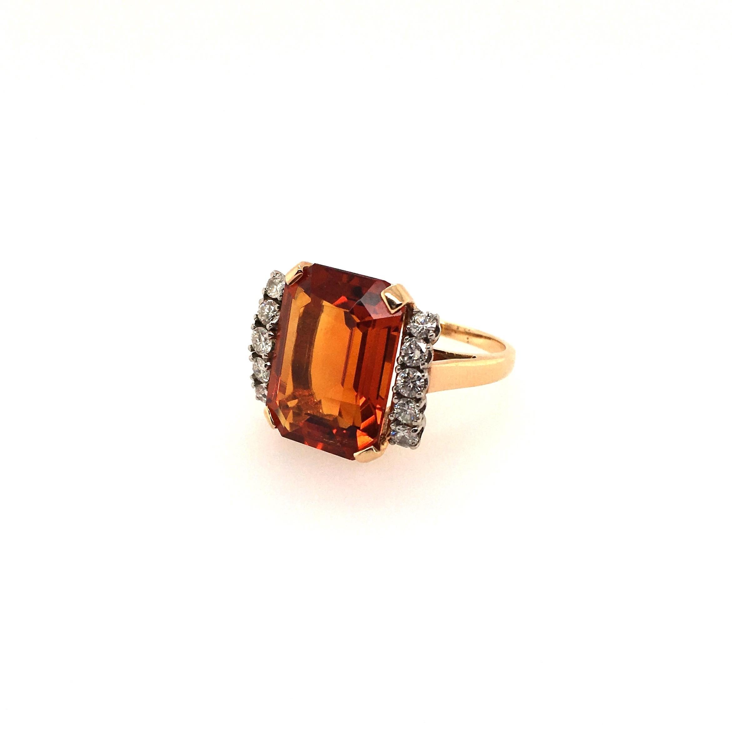 A 14 karat yellow gold, citrine and diamond ring. Set with an emerald cut golden orangen citrine, measuring approximately 16.00 x 12.50 x 7.4mm, and weighing approximately 9.85 carats, flanked by rows of circular cut diamonds. Ten (10) circular cut
