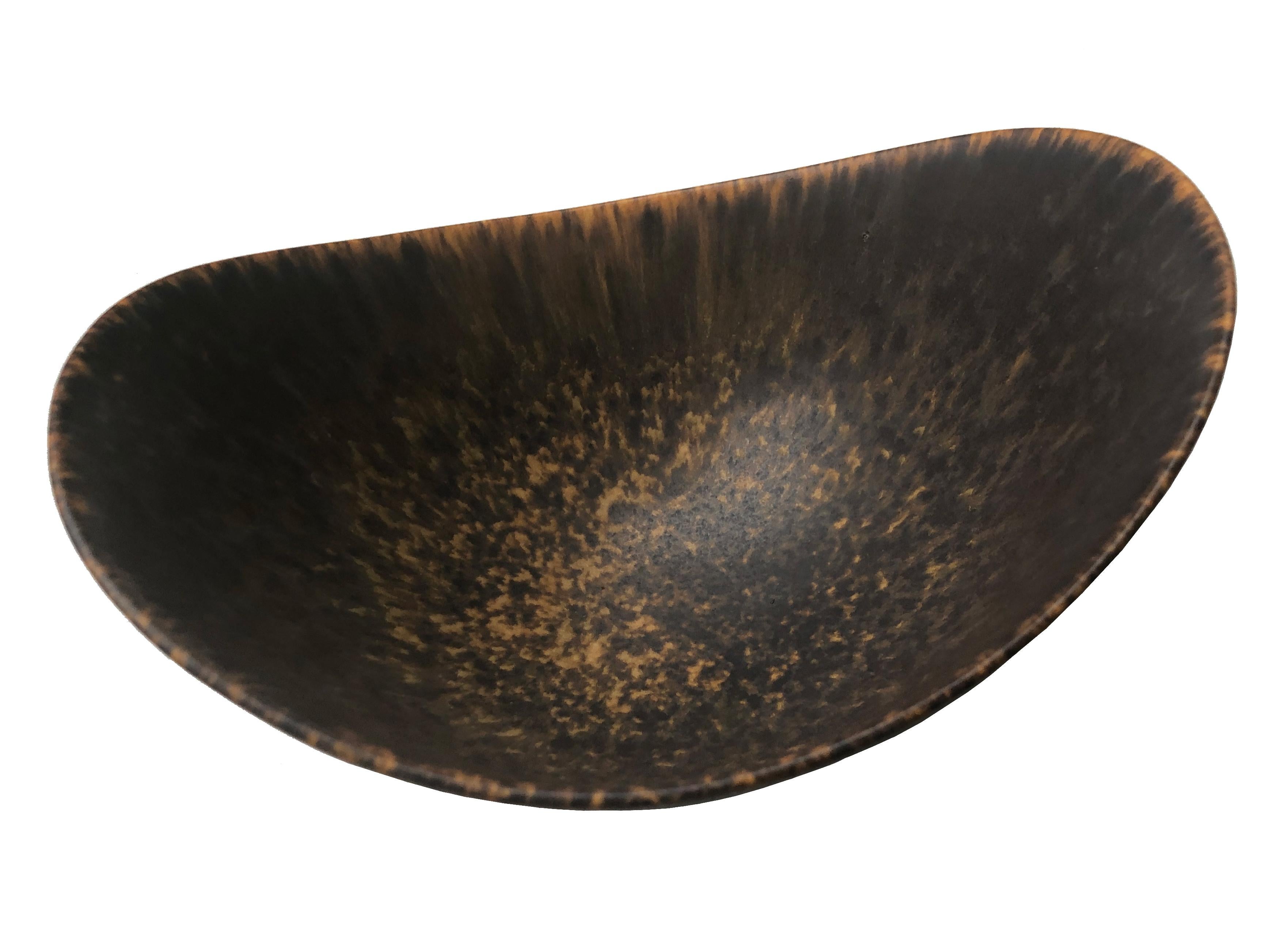 A Classic brown and beige-glazed stoneware bowl designed and produced in Sweden, 1940s. Marked as 1st quality. 
Gunnar Nylund, born in Paris in 1904 to parents engaged in sculpting and design, embarked on his own career as a designer at an early
