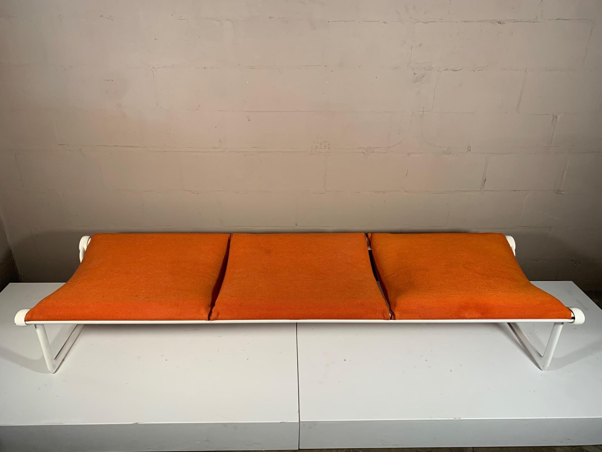 Un banco clásico de color blanco roto y tapicería naranja original, de Hannah Morrison para Knoll, hacia la década de 1970. El de tres plazas mide 81