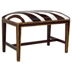 Banc de style classique doré et ébénisé, tapissé de faux cuir de vache zébré