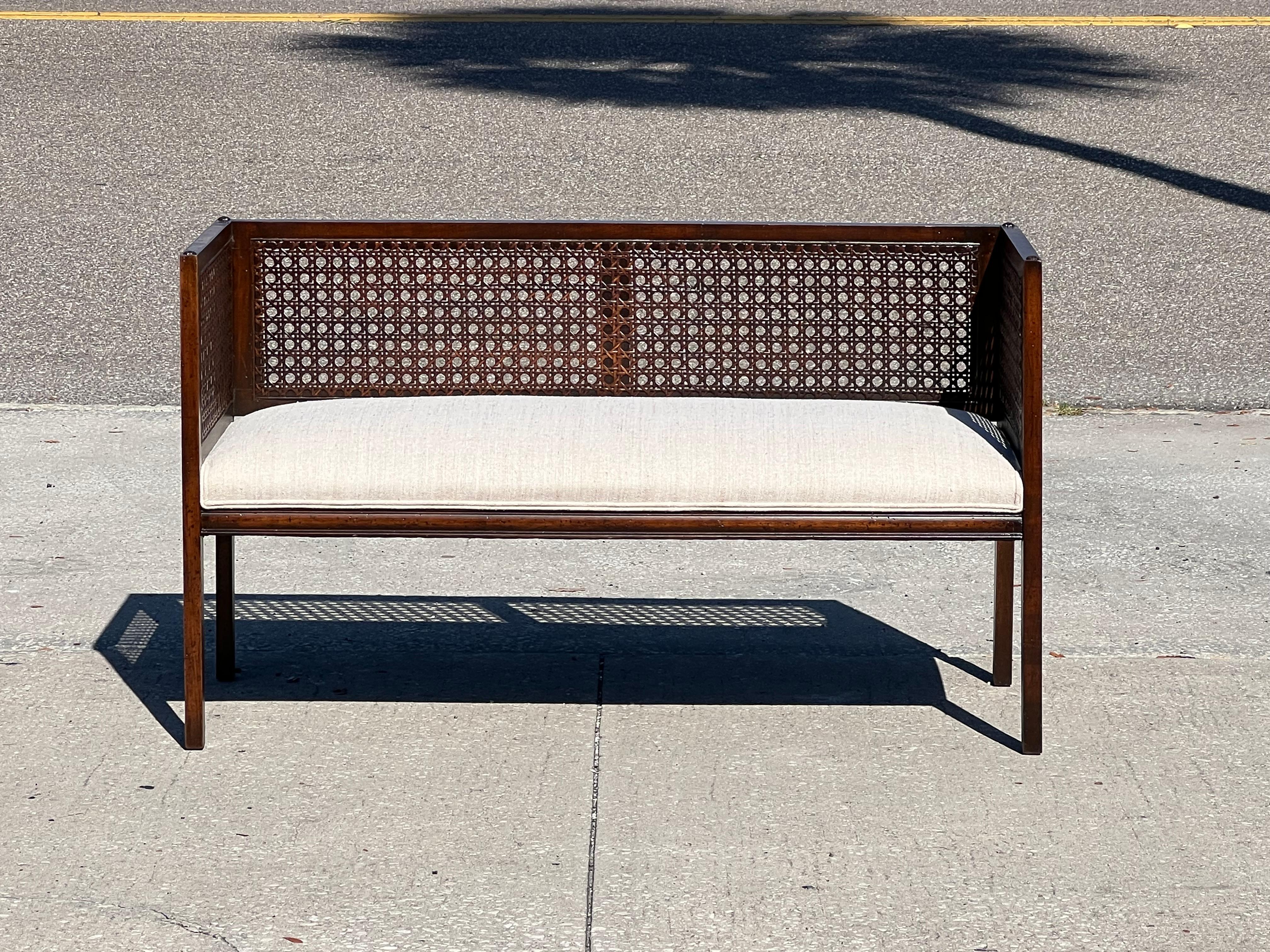 A classic upholstered bench with original speckled finish. Caned back, reupholstered in Larsen fabric.