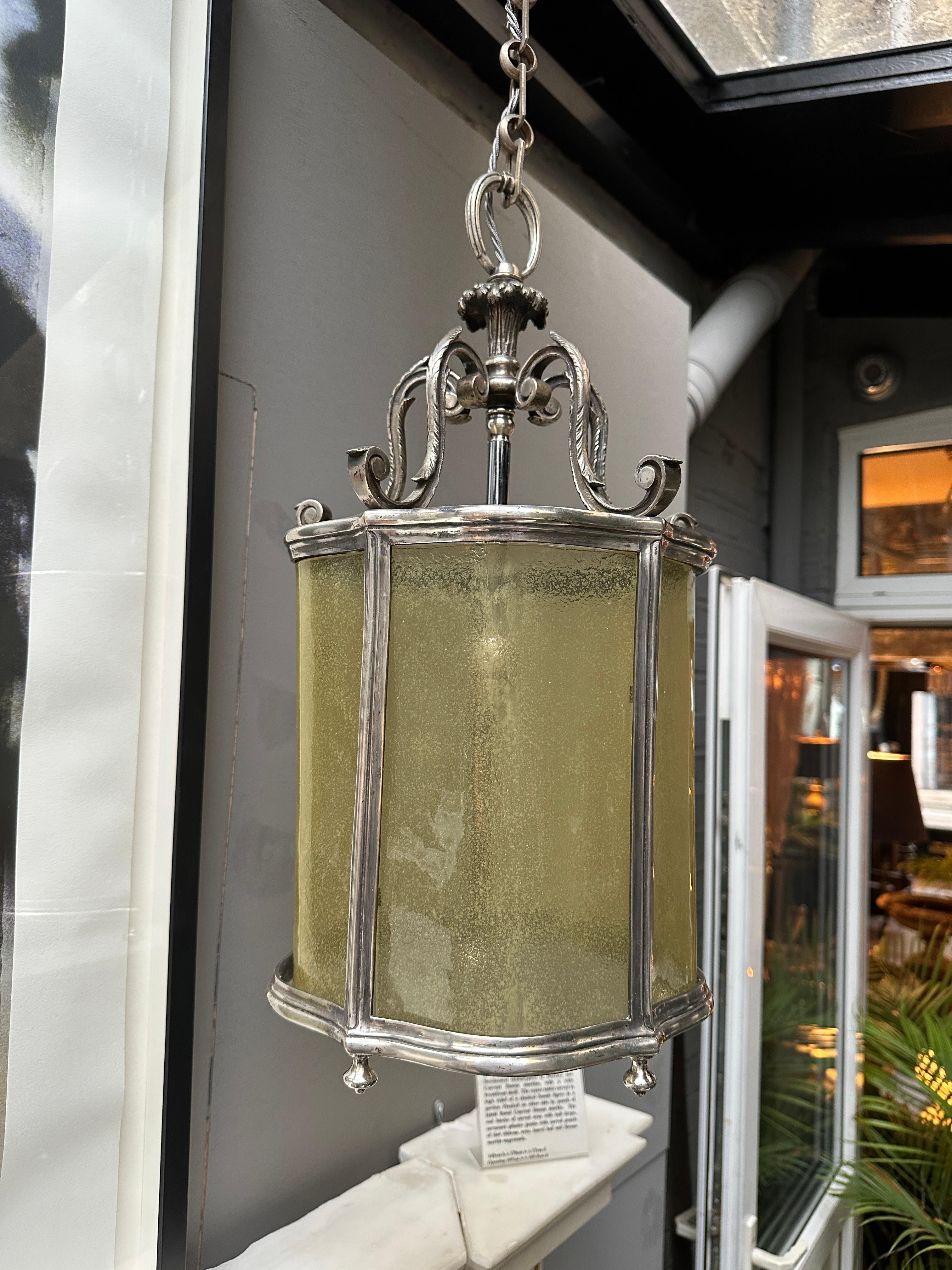 An Italian nickel and curved Murano amber glass lantern from the early 20th century. Very good quality casting and glass panels. The canopy with scrolled acanthus design. Finials to base. 45cm of adjustable chain included giving the overall drop of
