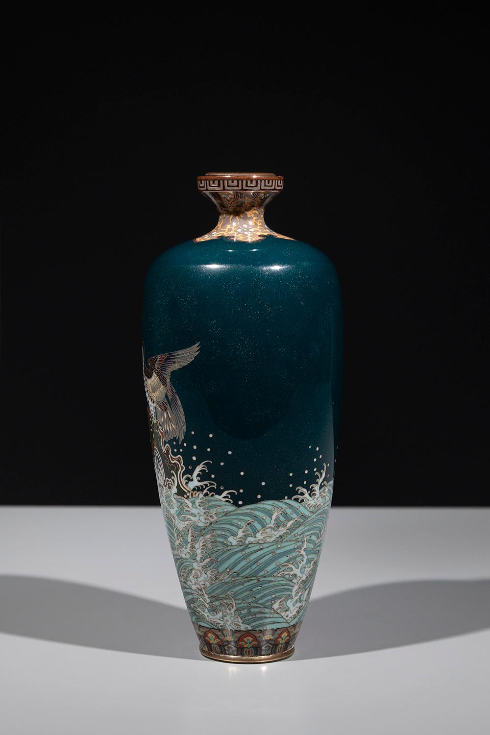 Vase cloisonné vert foncé décoré d'émaux aux couleurs vives, représentant un aigle majestueux perché sur un rocher au milieu des vagues, au moment de prendre son envol. La décoration est exécutée avec de fins fils d'argent soulignant les émaux,