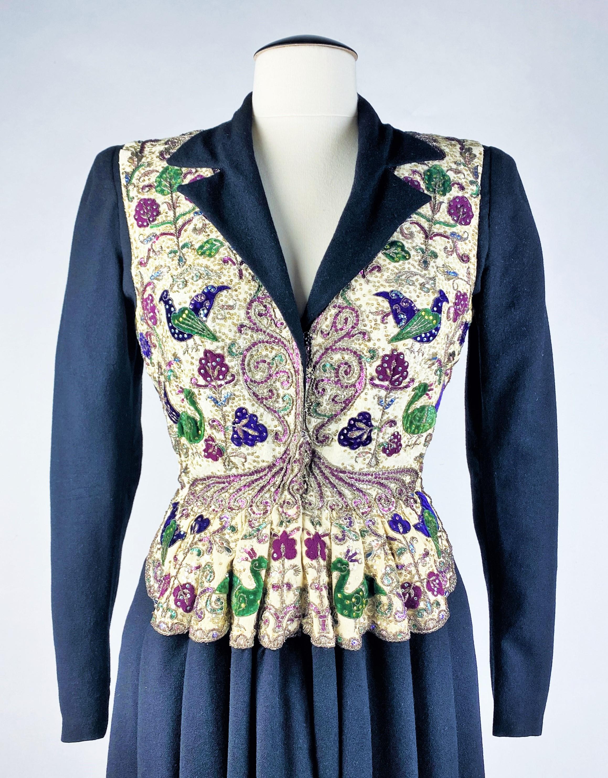 Circa 1945
Francia
Vestido o levita de lana negra bordada de la Maison Paquin dirigida por Antonio del Castillo. Corte entallado con mangas largas y escote en pico con paneles vueltos. Preciosos bordados orientalistas en el busto, que se ensanchan