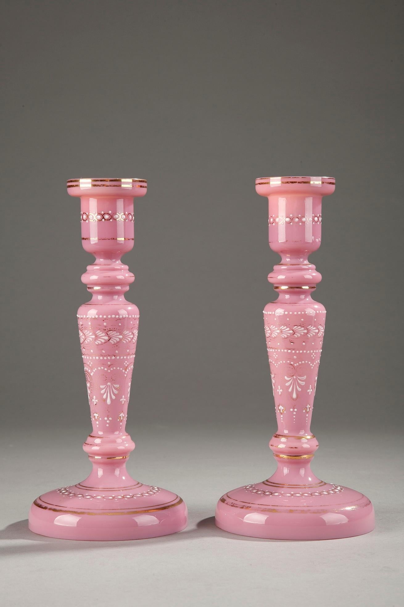A collection of 1850 pink opaline composed of:
1/ One flask decorated in white enamel with palmettes, small dots and floral motifs. Gold bands accent the base and the neck. The stopper is topped with a ball. Very delicate enamel work. Dimensions: L