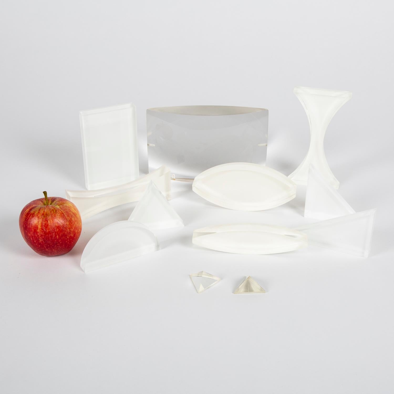 A collection of twelve Perspex teaching optical blocks and lenses.

Various shapes, forms and blocks, convex and concave, a number are backed with a white film.

Three have their original Griffin & George boxes.

