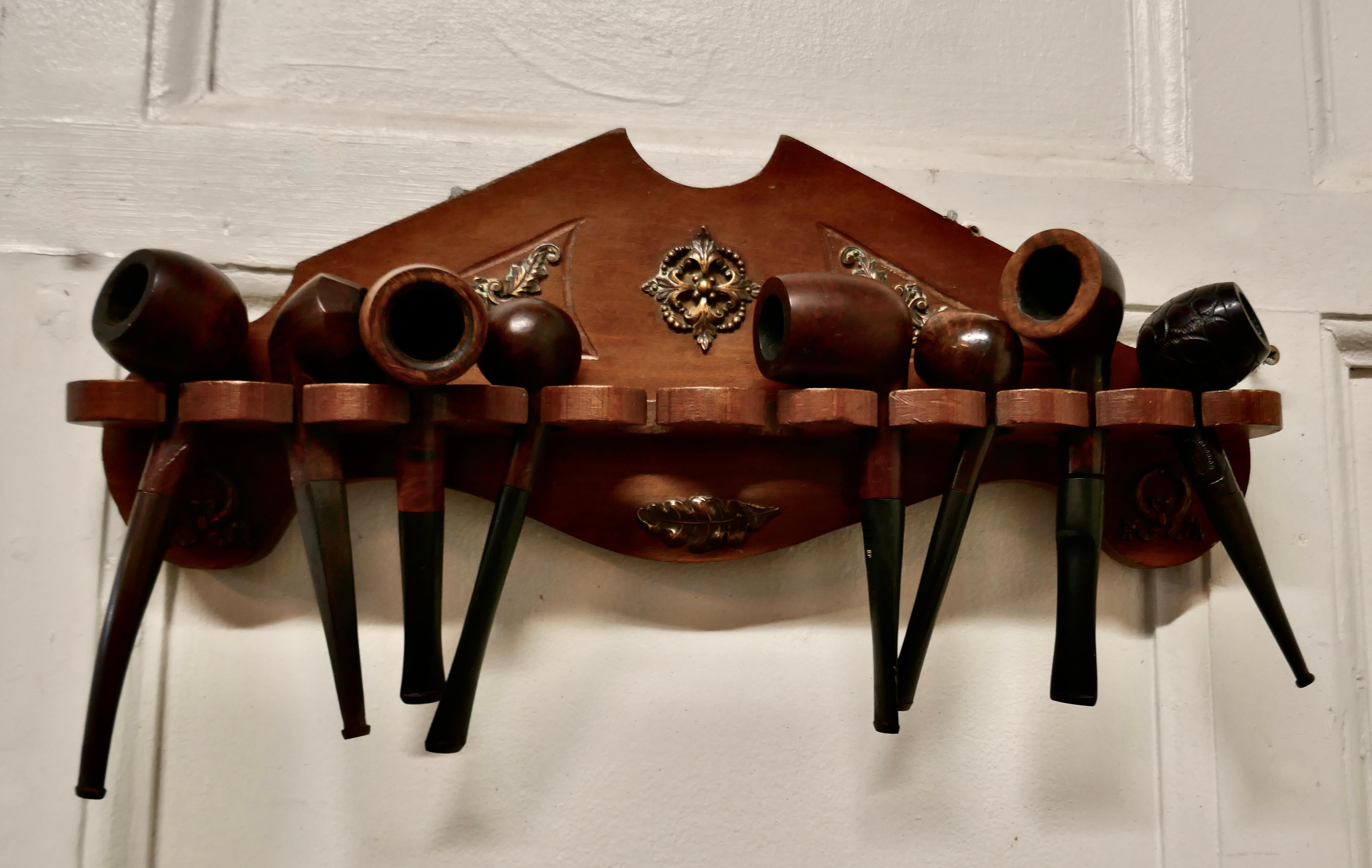 A Collection of 12 Vintage Tobacco pipes in a pipe rack

A good representative collection of used brier pipes, in a fruitwood wall hanging pipe rack, all in good used condition, the decoration of the pipe rack is in pressed Copper it is 10” high,