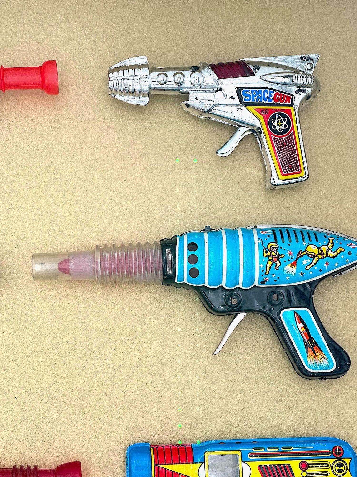Tin A collection of 1960s/70s tinplate and plastic ray guns mounted in a box frame. For Sale