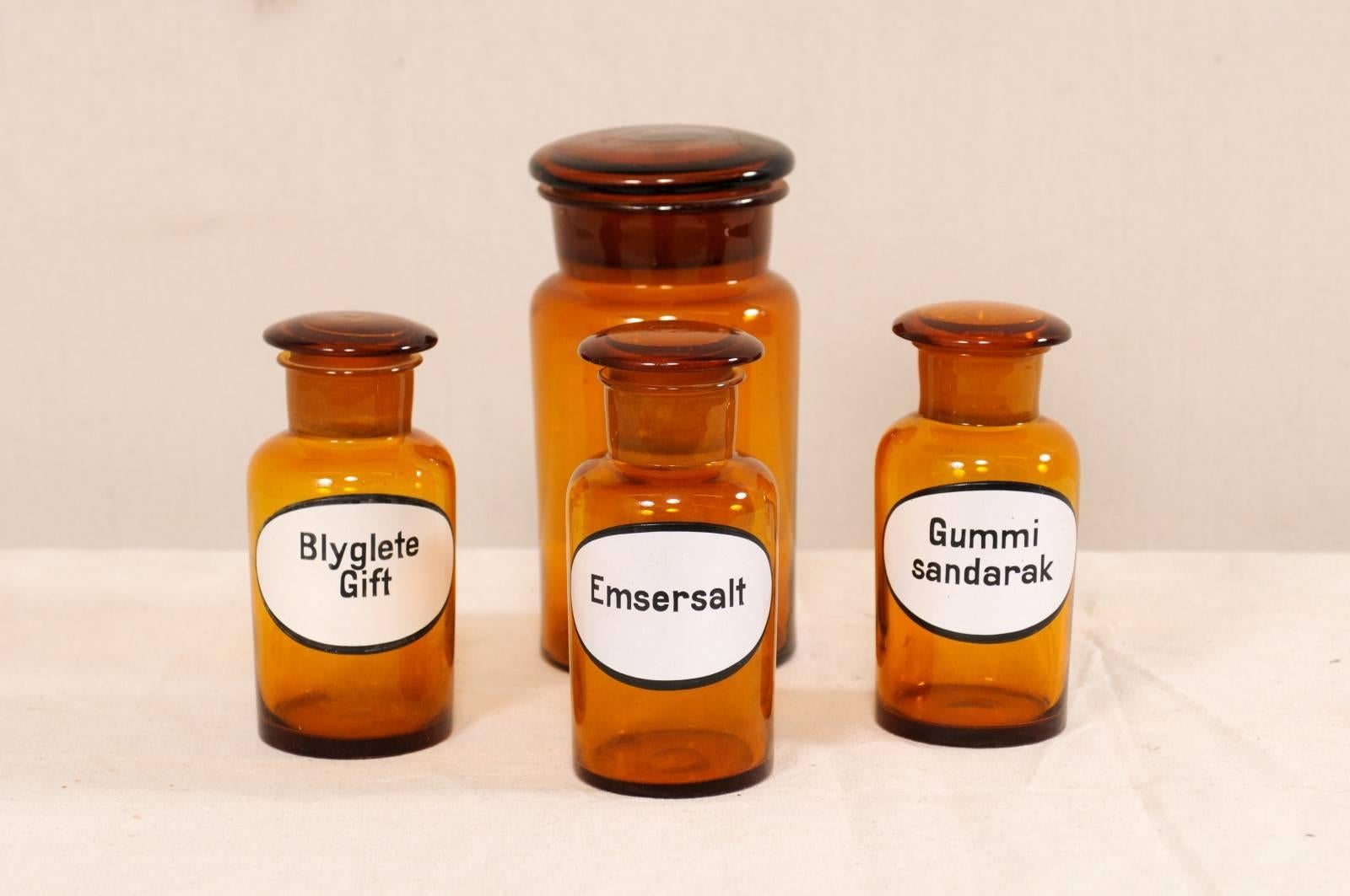 A collection of four Swedish apothecary jars from the early 20th century. These antique jars from Sweden were once used to hold an apothecary's (or pharmacists) wares and chemicals. This wonderful set of four jars, are each made of amber colored