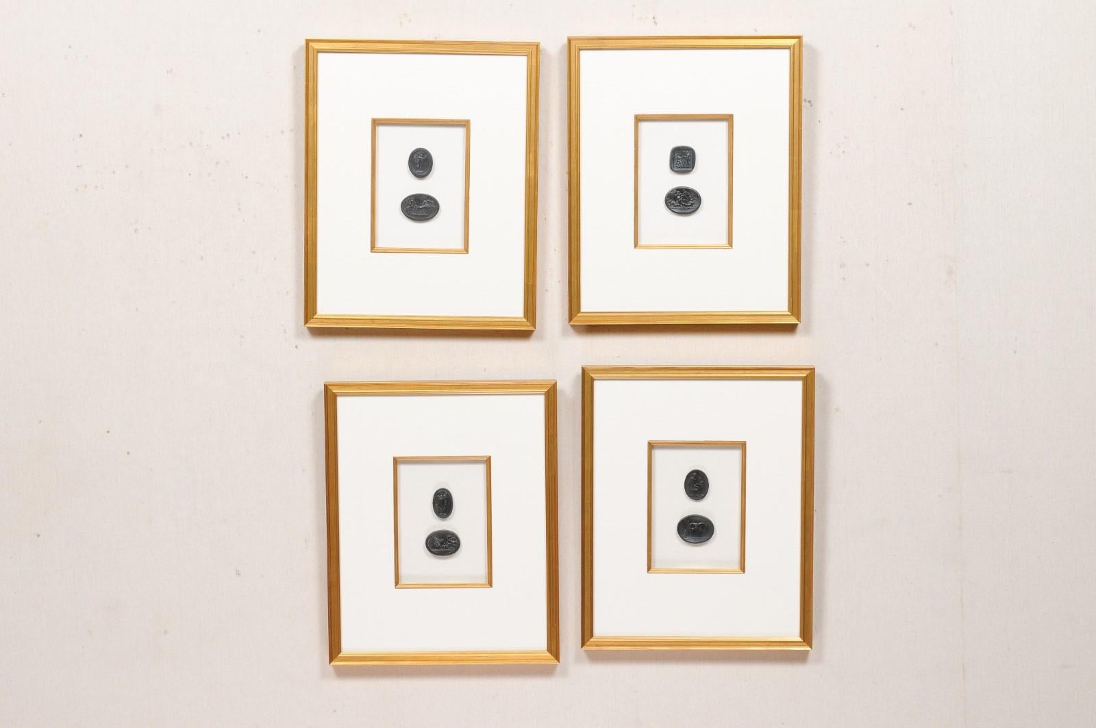 A collection of four art pieces of black intaglio seals, displayed nicely within custom gold toned wooden frames. This set of framed art each features a pair of black colored Italian intaglio seals (contemporary reproductions) which have been set