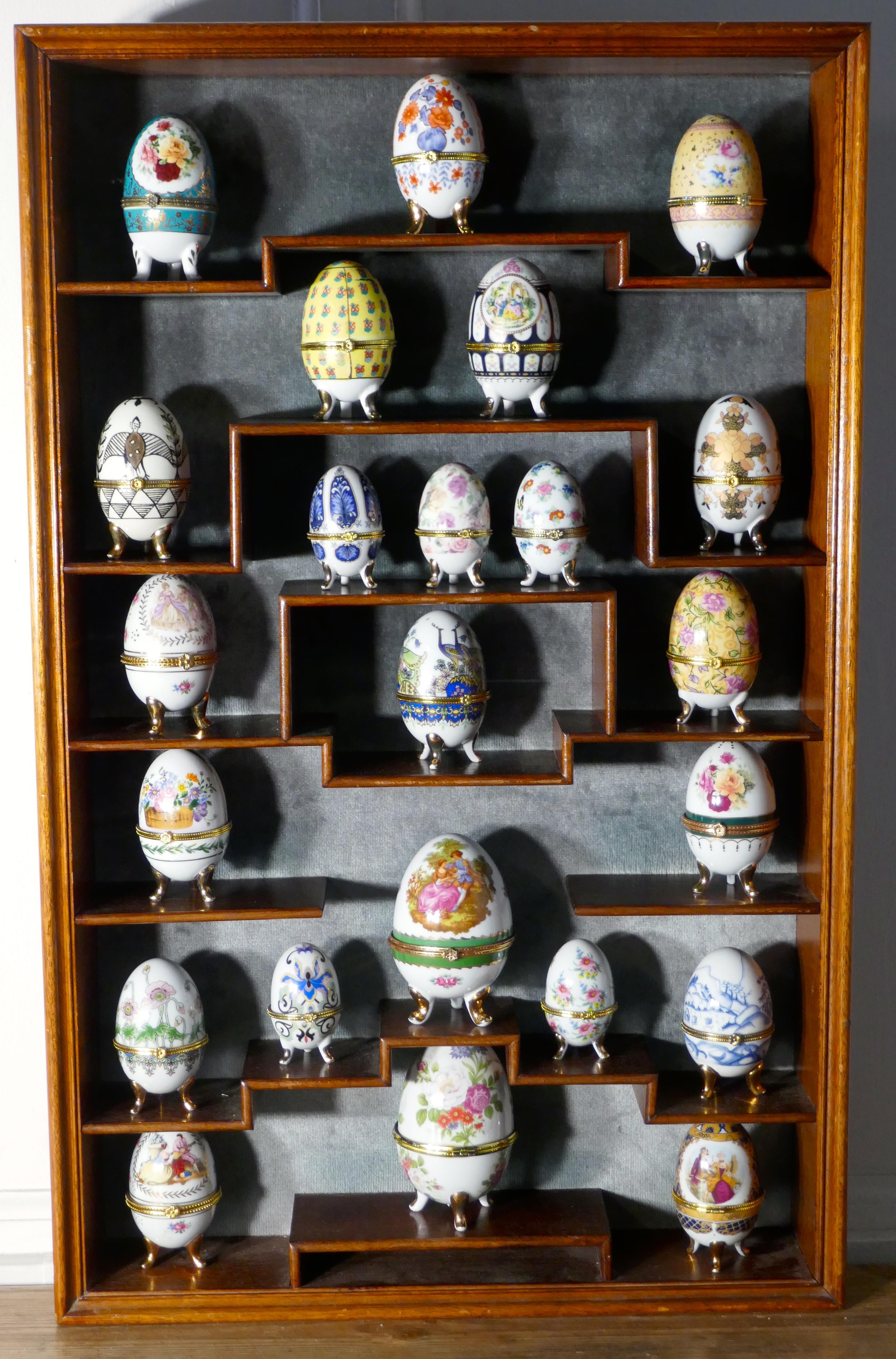 A collection of ceramic egg trinket boxes, in original Art Deco display shelf

This collection comes in its own wall hanging shelf unit, the shelf is made in mahogany with a blue velvet lining, the shelves are in the Odeon waterfall style all