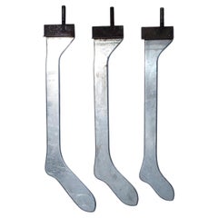 A collection of three different sized metal industrial sock or stocking forms. 