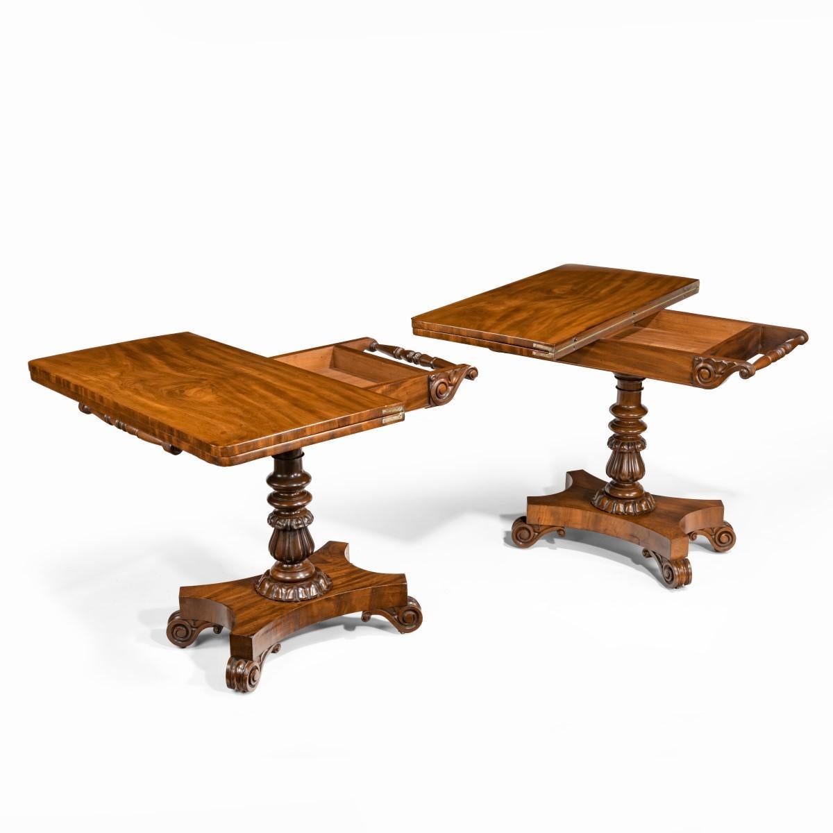 A companion pair of William IV flame-mahogany card tables, each the rectangular hinged top opening to reveal a green baize playing surface and a storage compartment, the frieze with carved acanthus scroll corners, all raised on a turned and