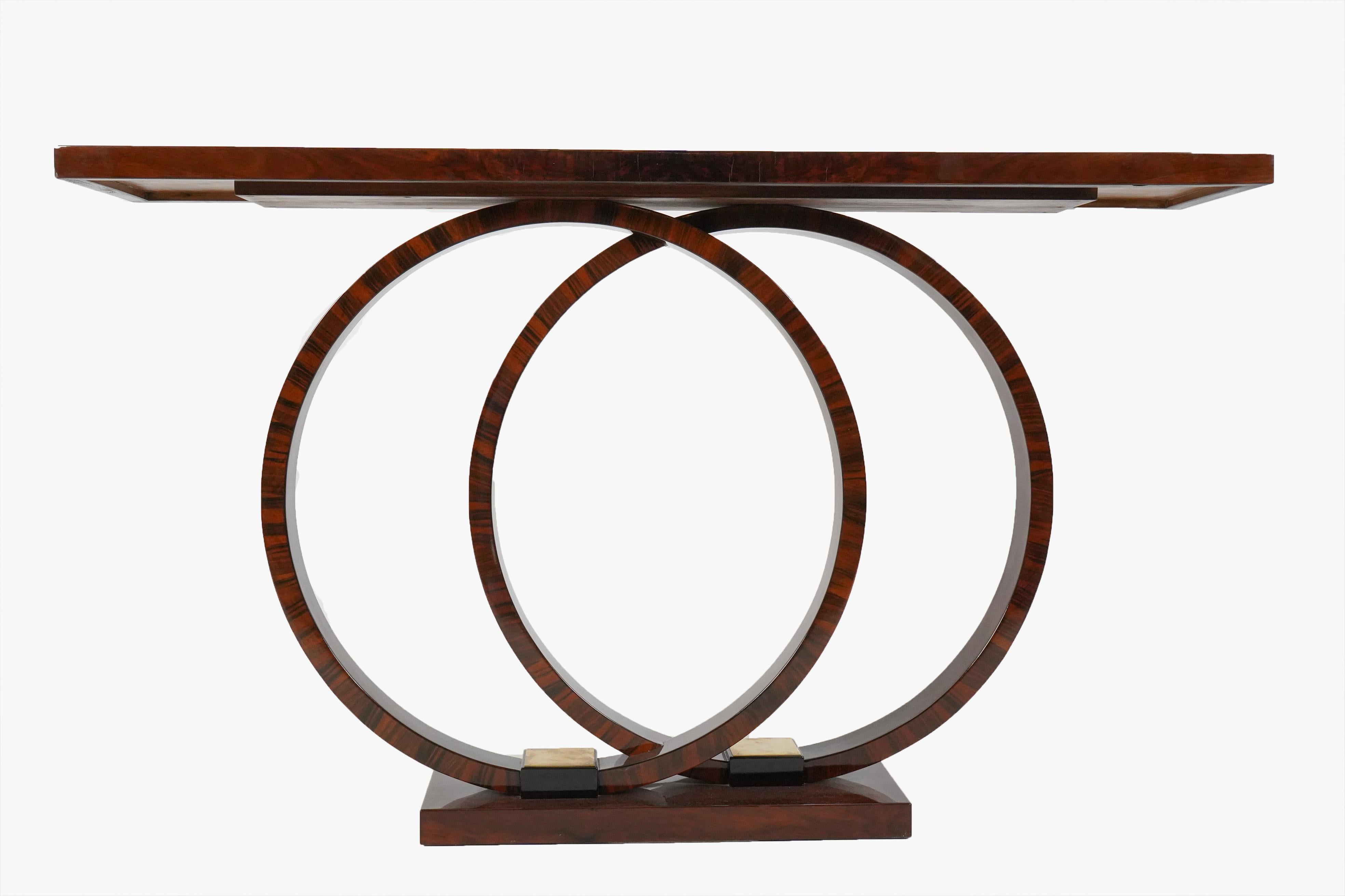 This stylish console features walnut veneers and nickel fittings. The top is finished in a very glossy French polish and rests atop two offset circular legs, also finished in walnut veneer. The piece is hard to categorize -not traditional enough for