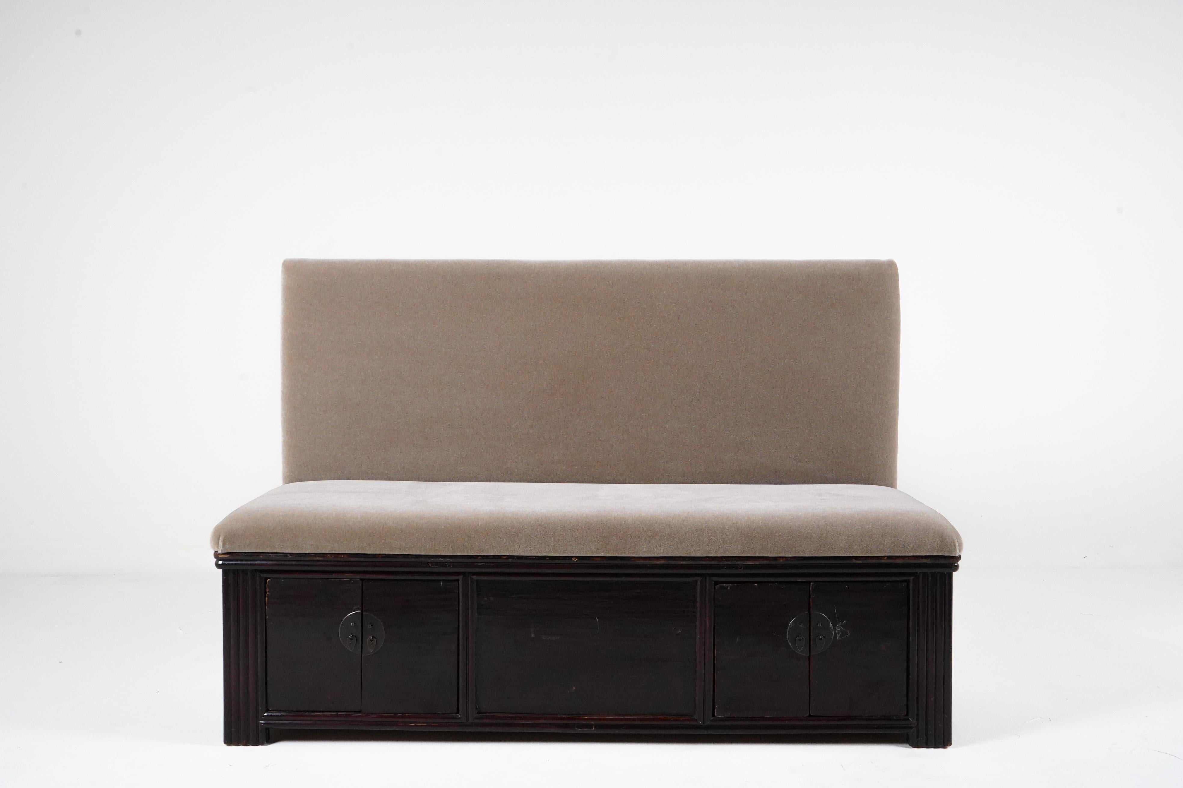 This unique upholstered bench is built on an antique Chinese Kwang chest. The chest dates to the 19th century and is made from elm wood covered in dark oxblood lacquer with a French polish surface. The seat and seatback is covered in mohair. At only