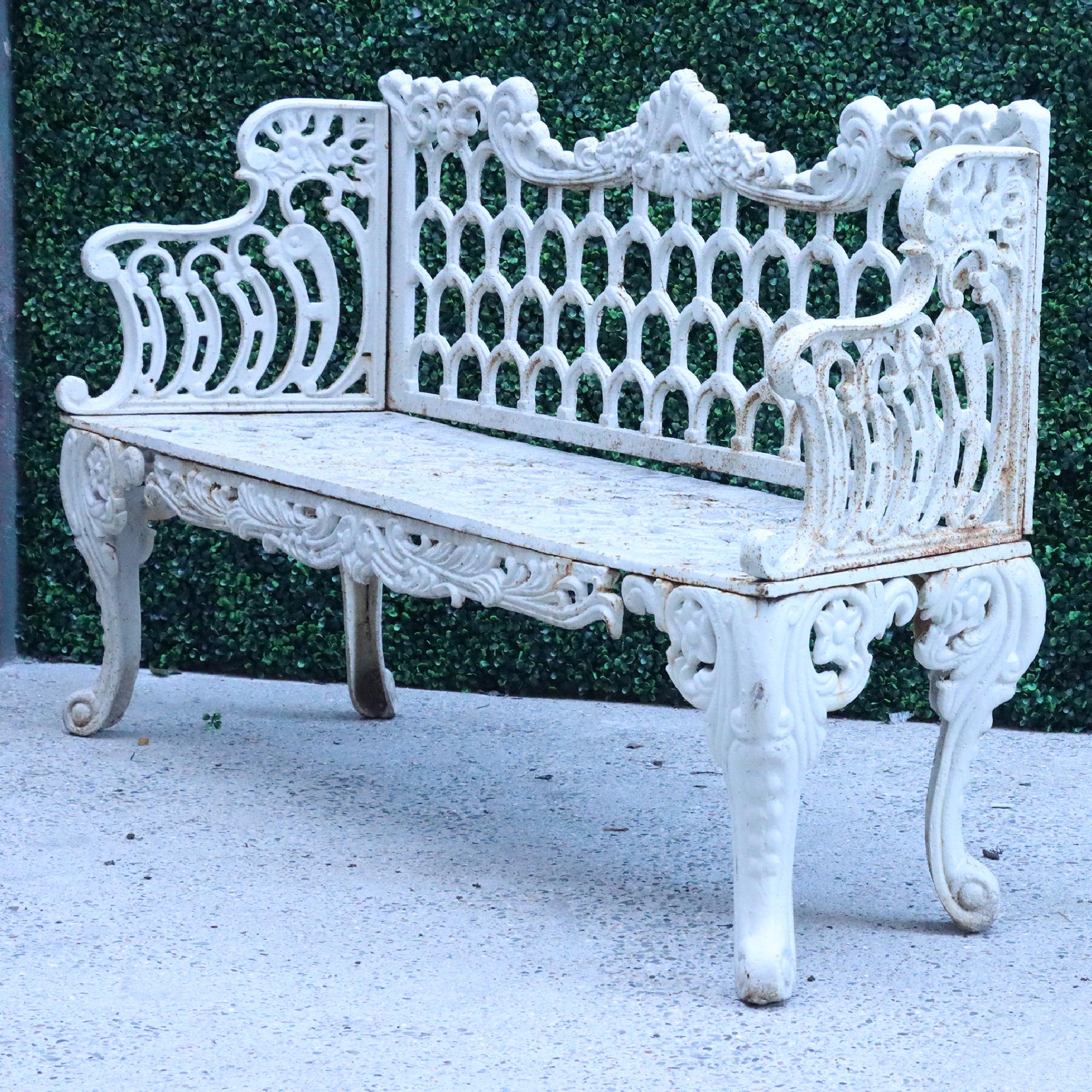 A contemporary cast iron garden bench in white. Floral and scroll design crest rail over arch. Decorated back flanked by stepped arms above seat supported on cabriole legs.