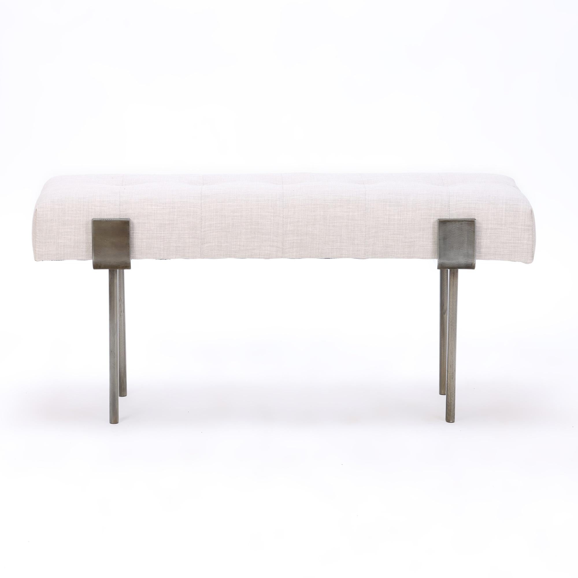 A contemporary iron bench with linen upholstery. Bronze wash base.