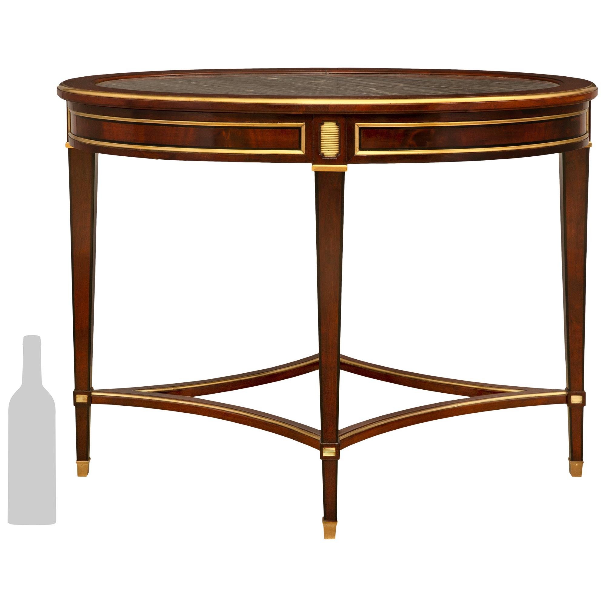 A handsome Continental 19th century Directoire st. Mahogany, ebonized Fruitwood, Brass, Ormolu and Gris St. Anne marble side/center table. The table is raised by four square tapered legs in Mahogany with ebonized Fruitwood bands at the four corners.
