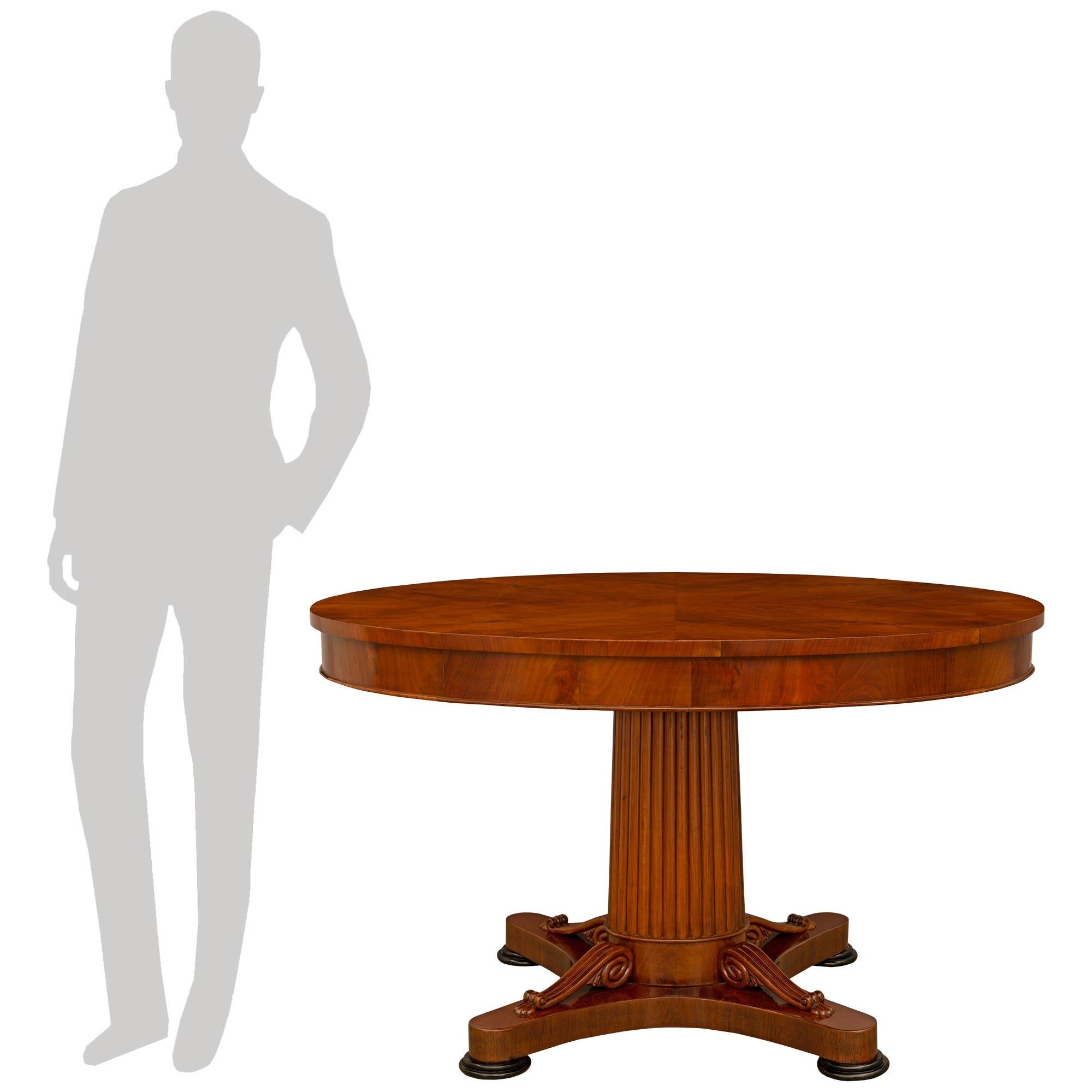 Una llamativa y bellísima mesa central continental de caoba y frutal ebonizado de principios del siglo XIX, de estilo Imperio. La maravillosa mesa se eleva sobre patas de bollo de madera de frutal ebonizada, bajo el bastidor de lados cóncavos
