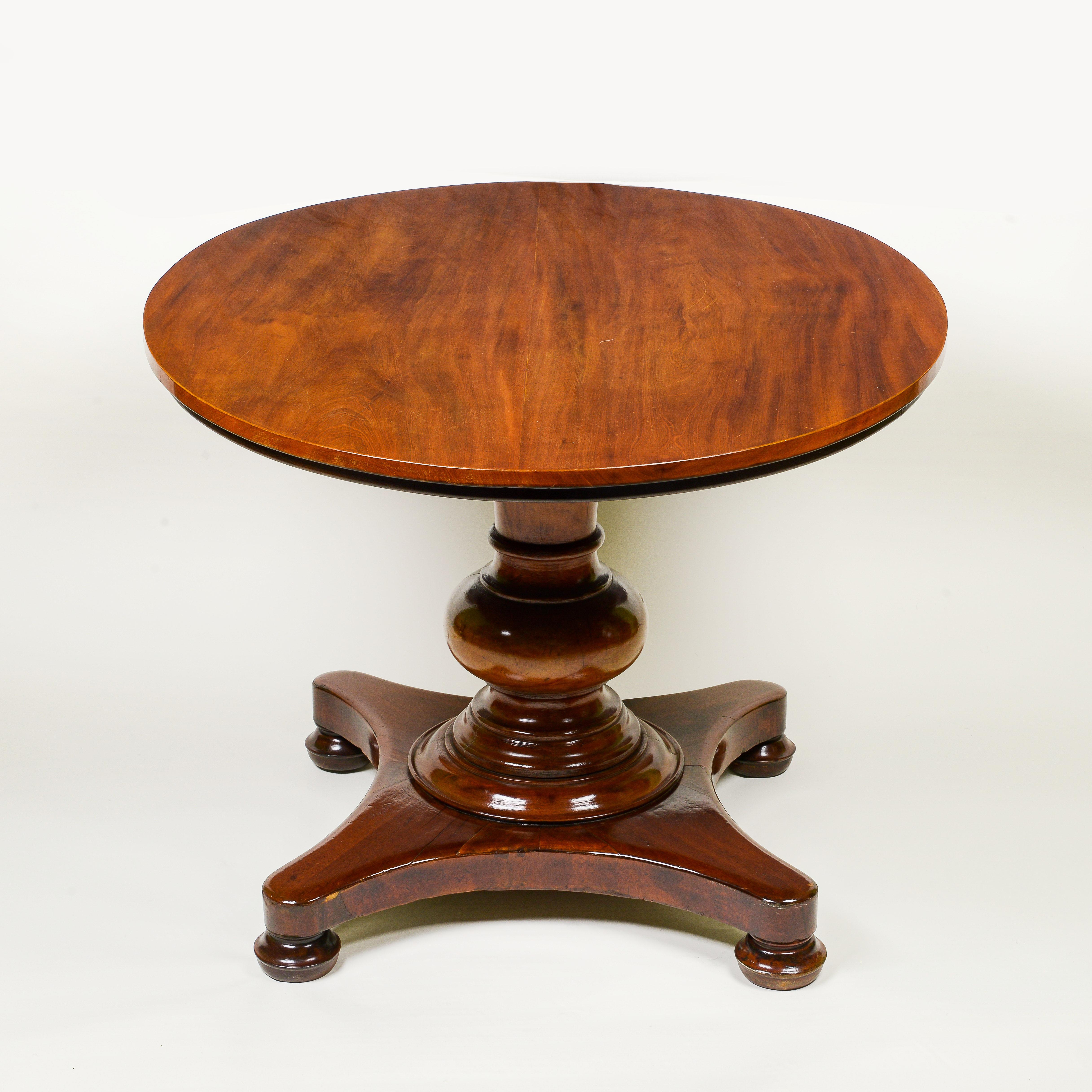 The oval tilt-top over a bold turned support on scroll-form feet.
