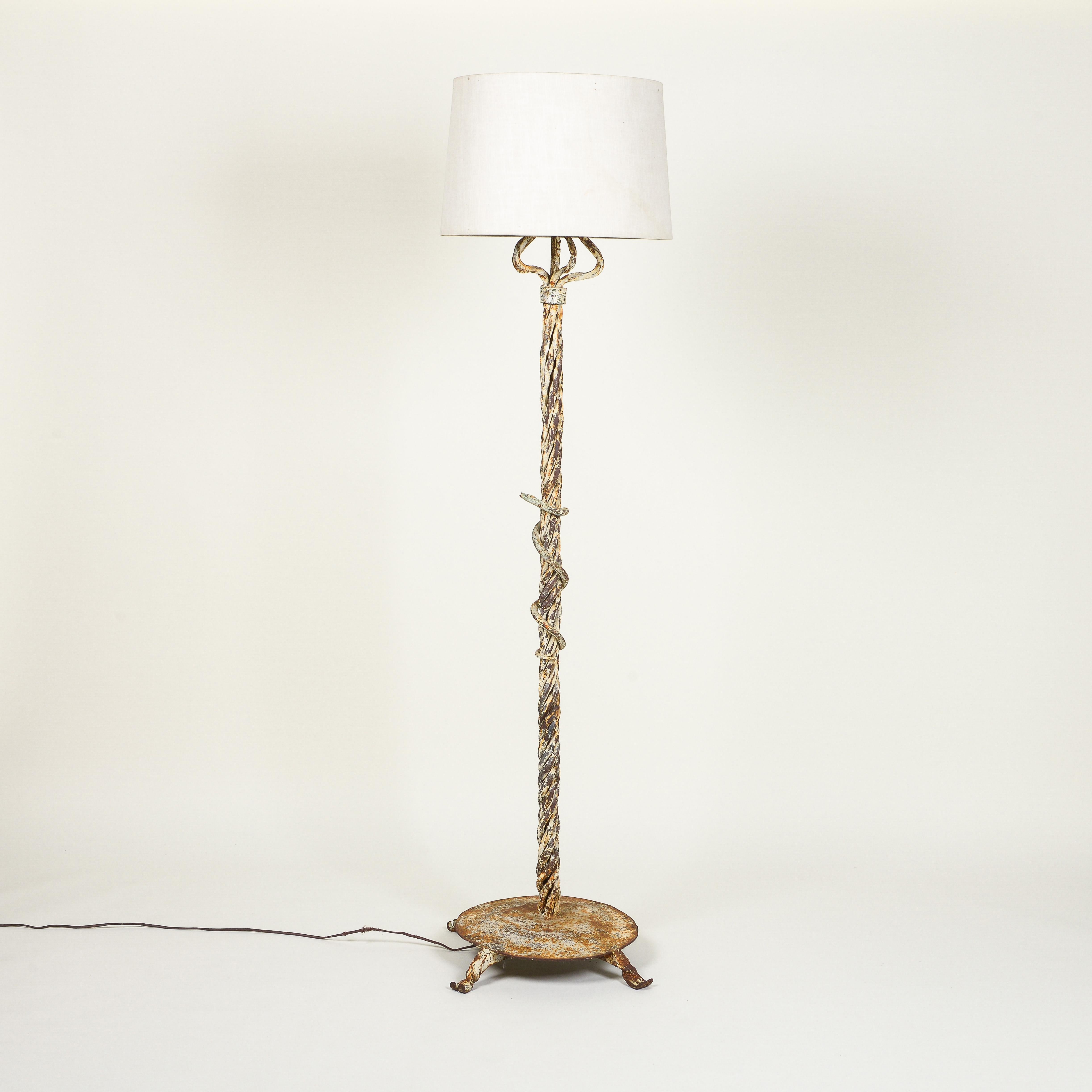 Of columnar form comprised of intertwined strands and fancifully wrapped with an asp; on a round plinth base and outscrolled feet. Fitted with two bulb sockets. With vintage linen shade.