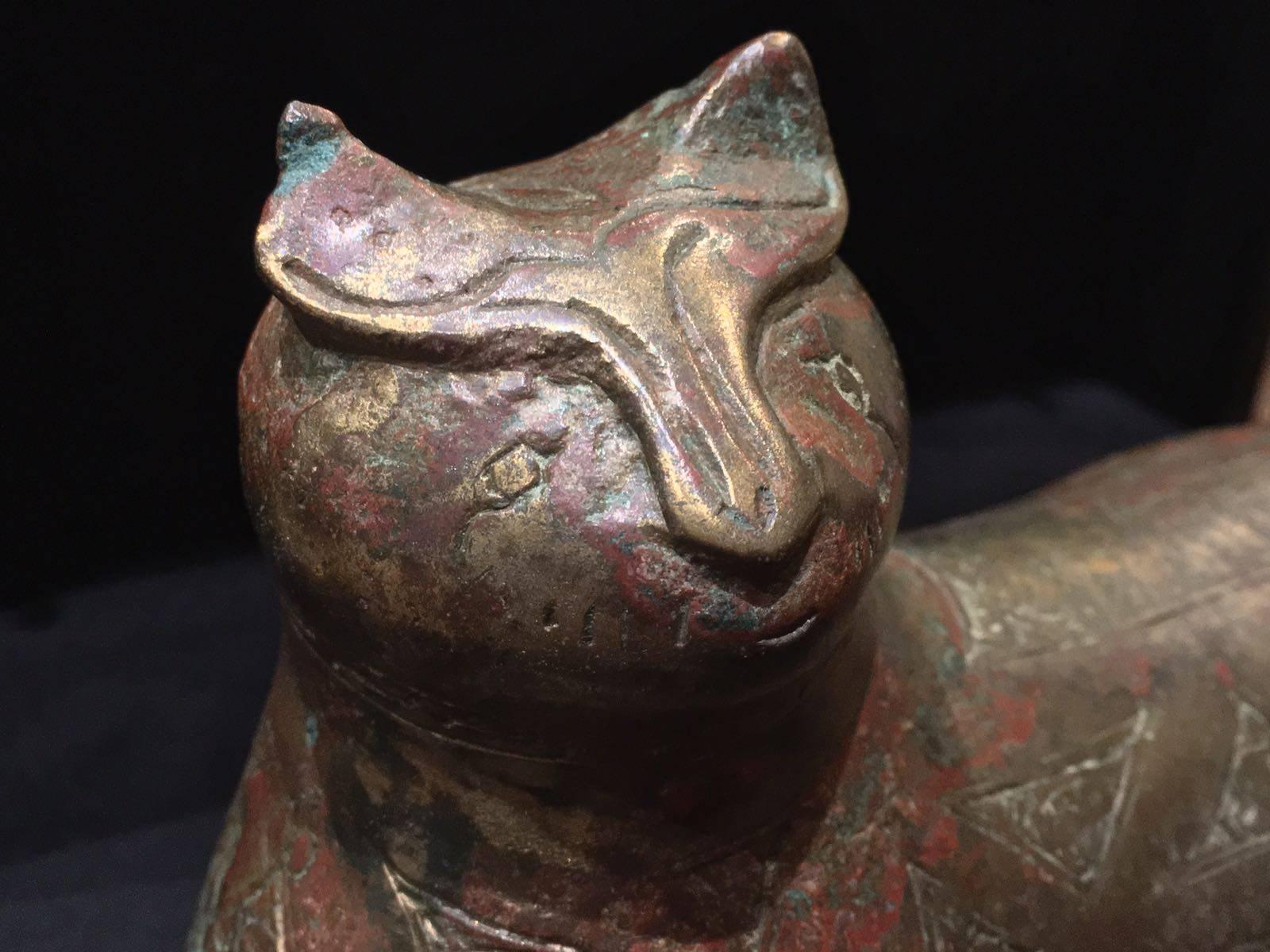 A copper-inlaid bronze weight in the form of a lion, Khurasan,
12th century.

Cast in the form of a reclining lion with forepaws outstretched, the body decorated with incised cartouches filled with inscriptions, crescent motifs and