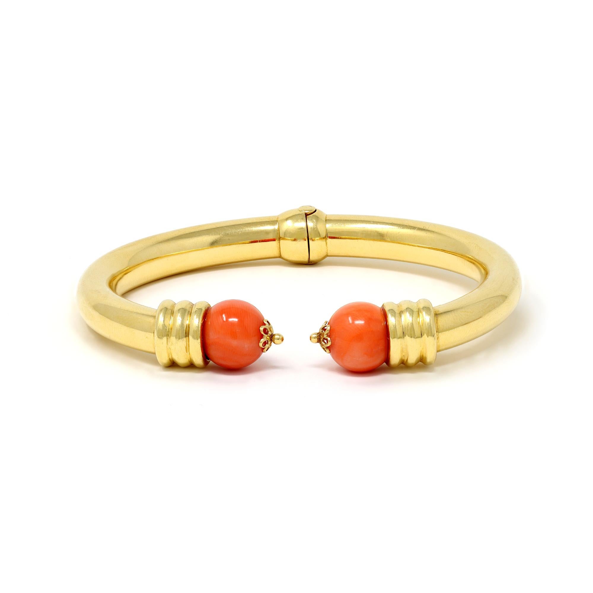 A classic bangle from the glorious 1980, with a tubular hinged shank, finished with 2 natural coral beads of a deep salmony color. The bracelet is set in 18 karat yellow gold and has a gross weight of 35.1 grams. It fits a wrist of 6.25”.