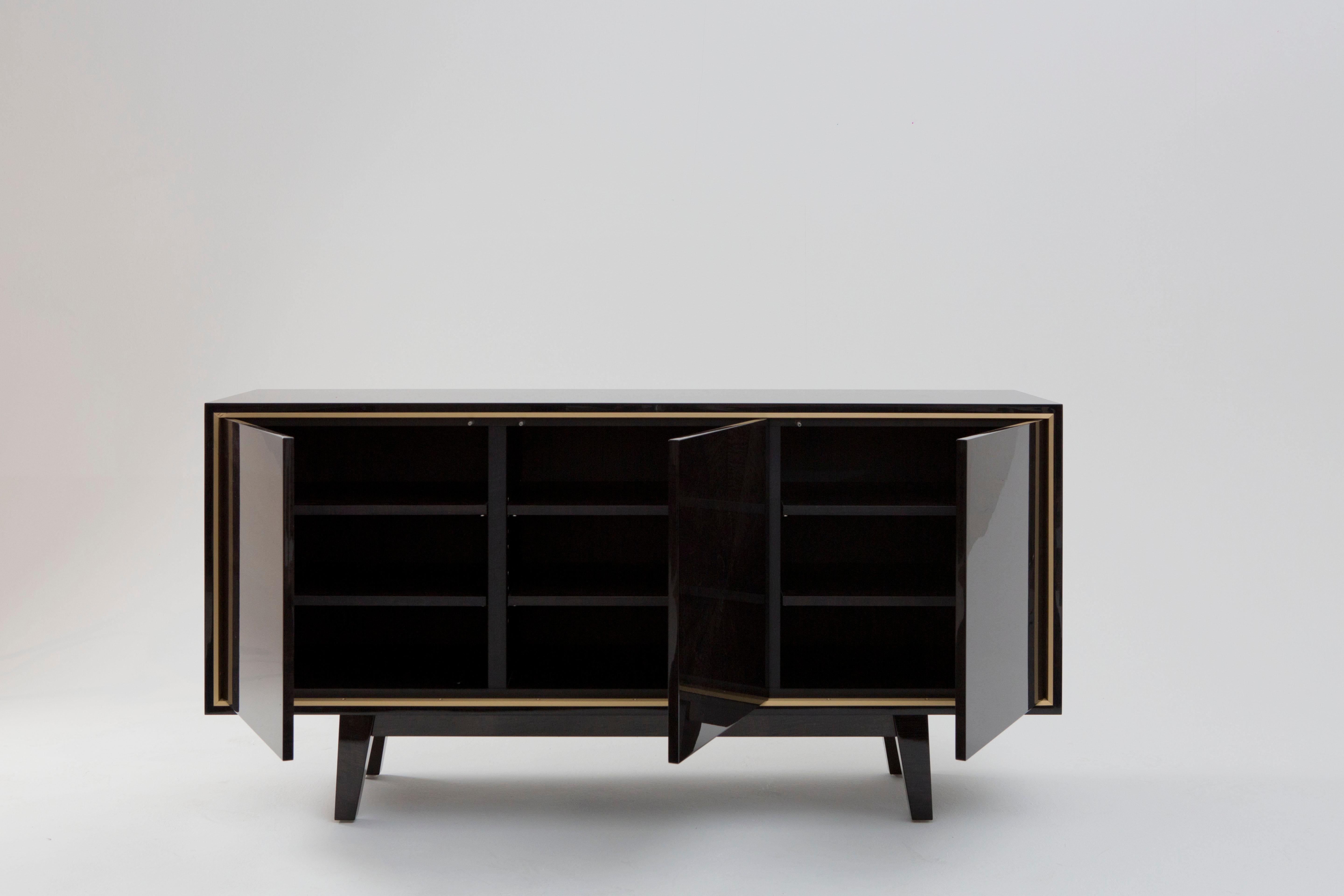 An exquisite side cabinet of sleek proportions that will look superior in any fine dining room or hallway.
The cabinet is finished in a beautiful dark and lustrous hand tinted sycamore with brushed brass trim. The interior of the cabinet also