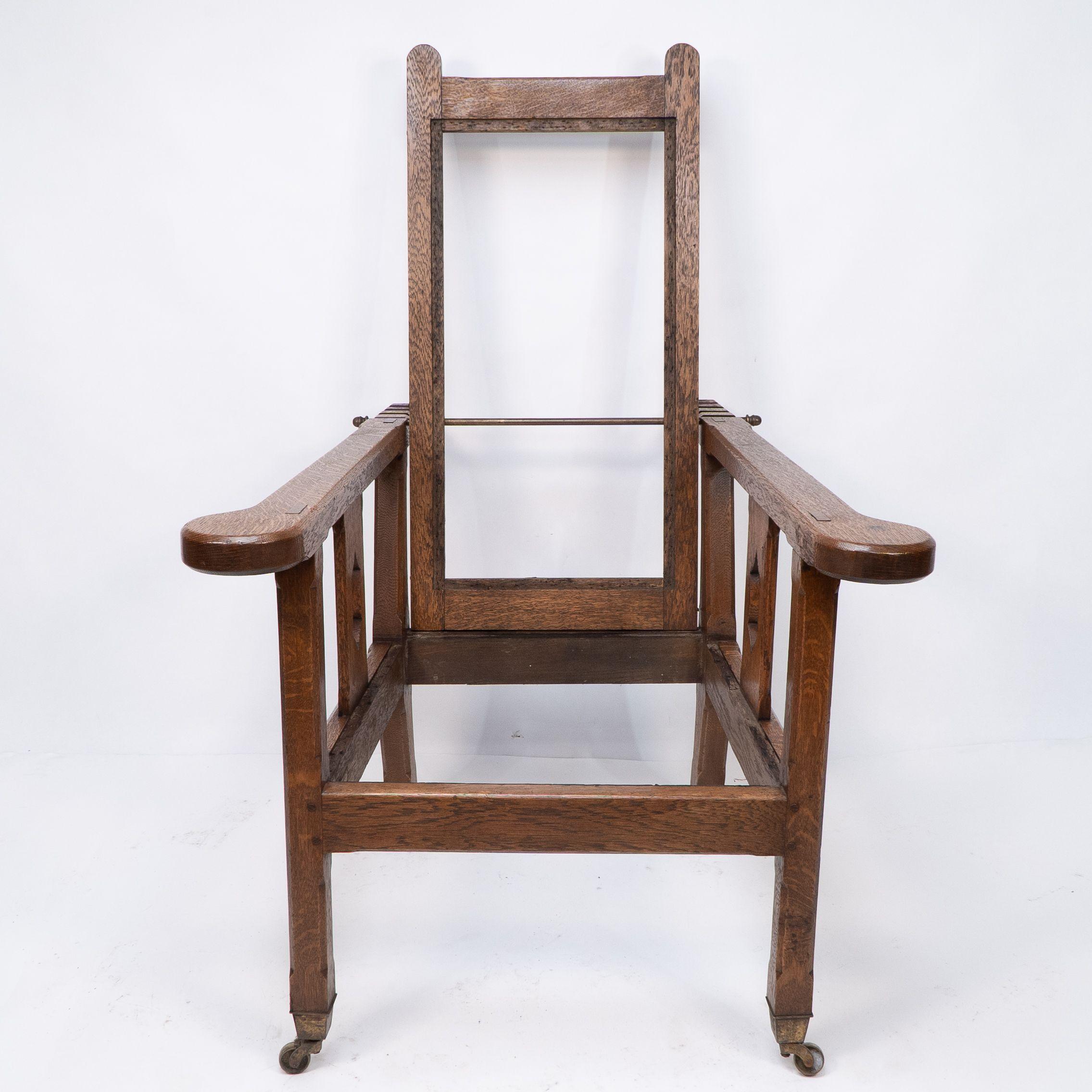 A Cotswold School Arts and Crafts reclining oak armchair of superior quality. With exposed through 'wedged' tenons and exposed dowel construction throughout, and fine chamferred edges which lightens its masculine design. Retaining the original brass