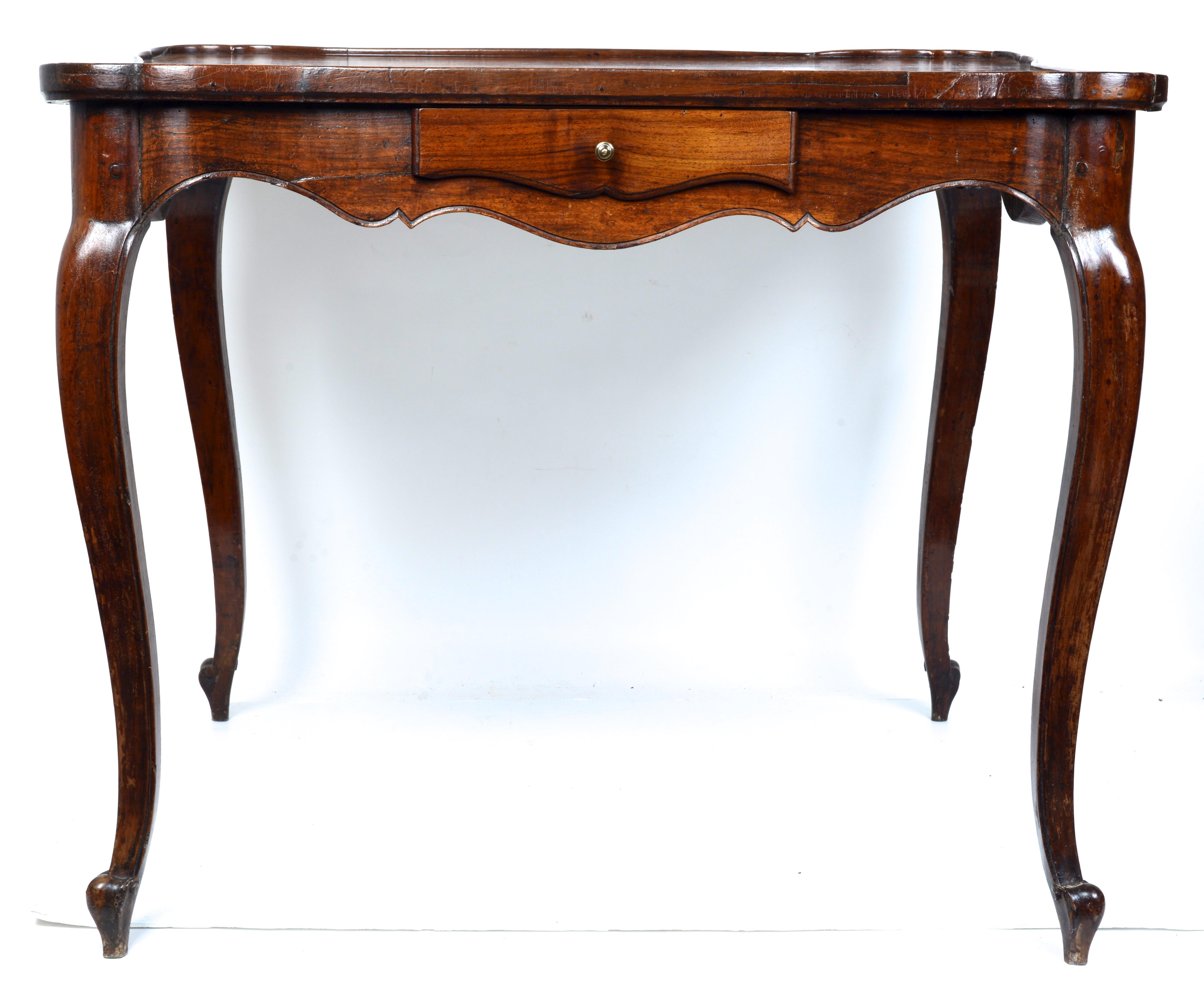 A.I.C.C. Table à jeux en noyer d'époque Louis XV Milieu du XVIIIe siècle. Le plateau en forme avec des coins tournés et un bord mouluré en relief est coupé dans deux planches qui se reflètent l'une l'autre le long d'une ligne centrale. Cette
