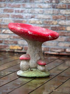 A couple of concrete Red Vintage Garden Mushrooms shaped stools with patina.